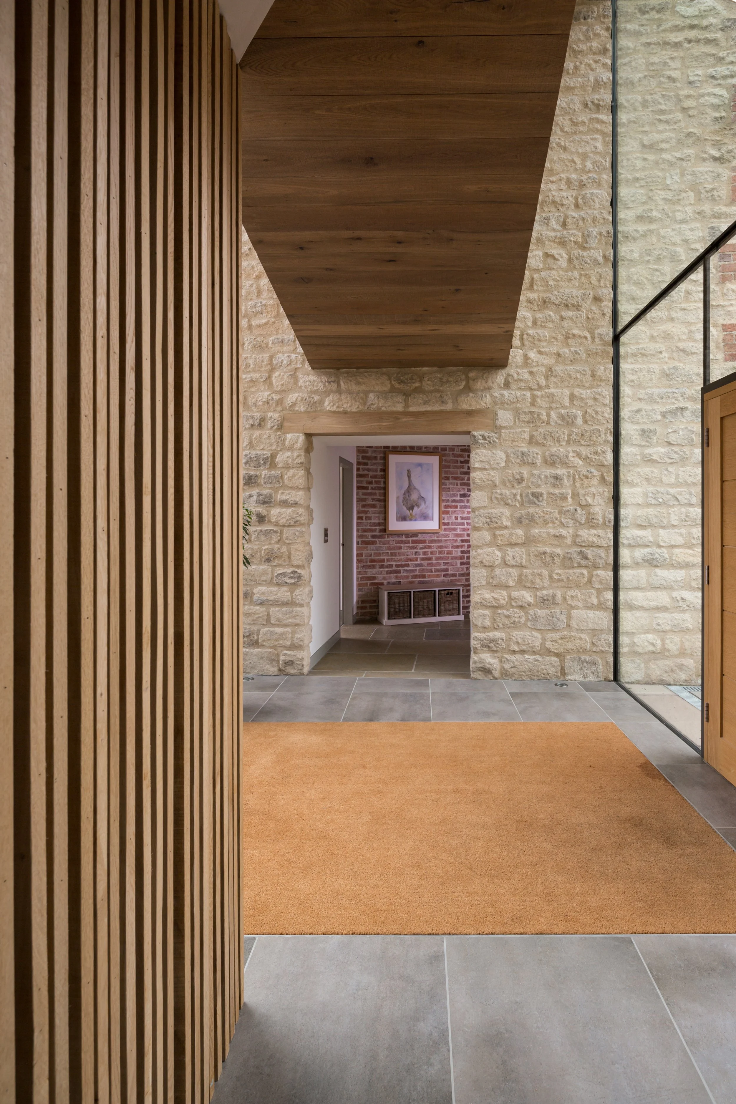 glazed intrance hall with large coir mat and floating first floor timber clad walkway above