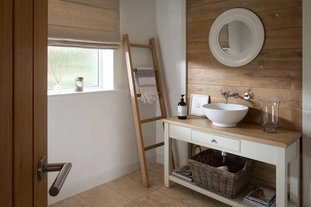 lifestyle image through the bathroom door looking at the wooden sink unit and wooden ladder style towel rail