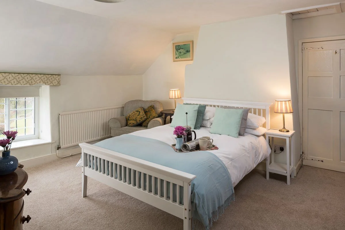 lofted ceiling bedroom with white walls, wood frame bed with pale blue bedding 