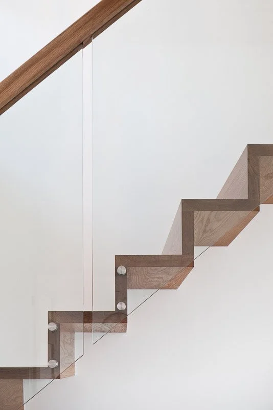 One point perspective of wooden staircase with glass banister 