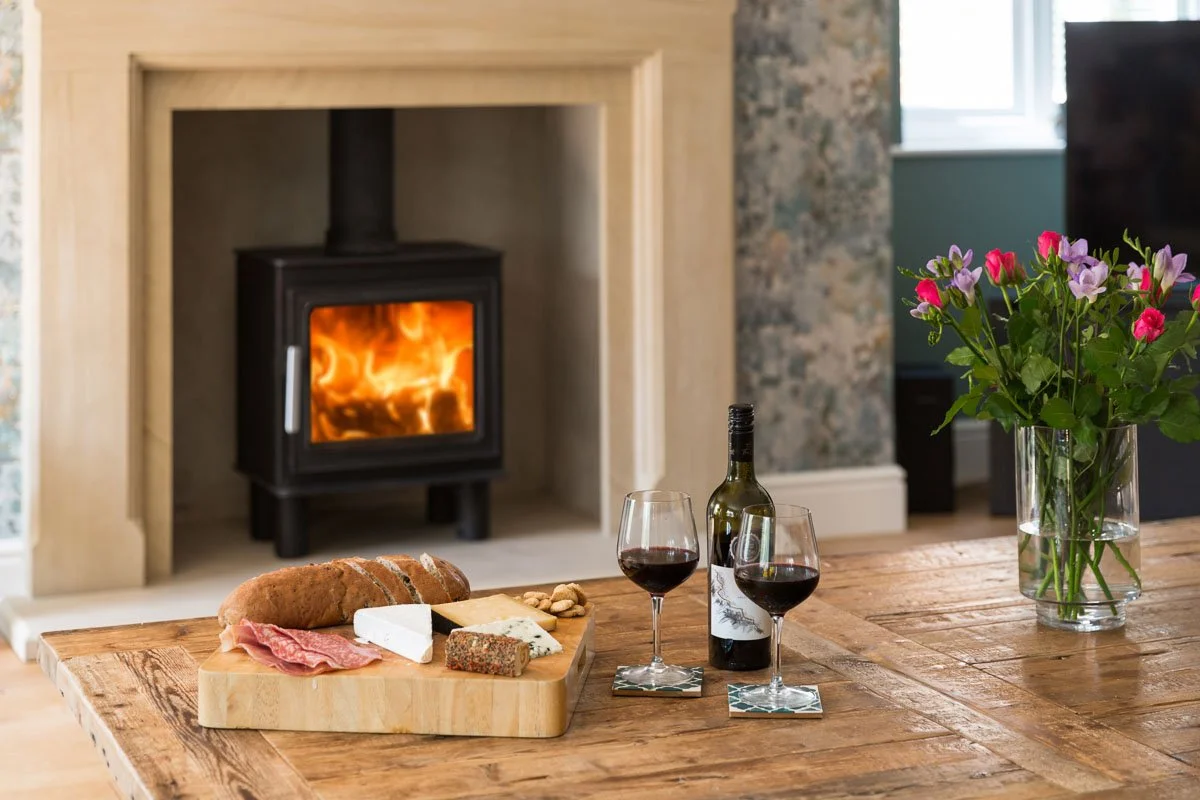 detail shot of coffee table in living room with charcuterie board, glasses of wine and log burner behind 