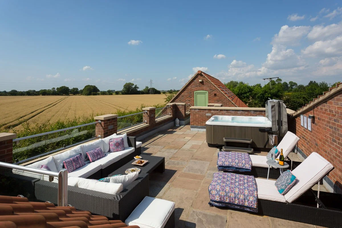roof terrace with sunbeds and hot tub overlooking fields 