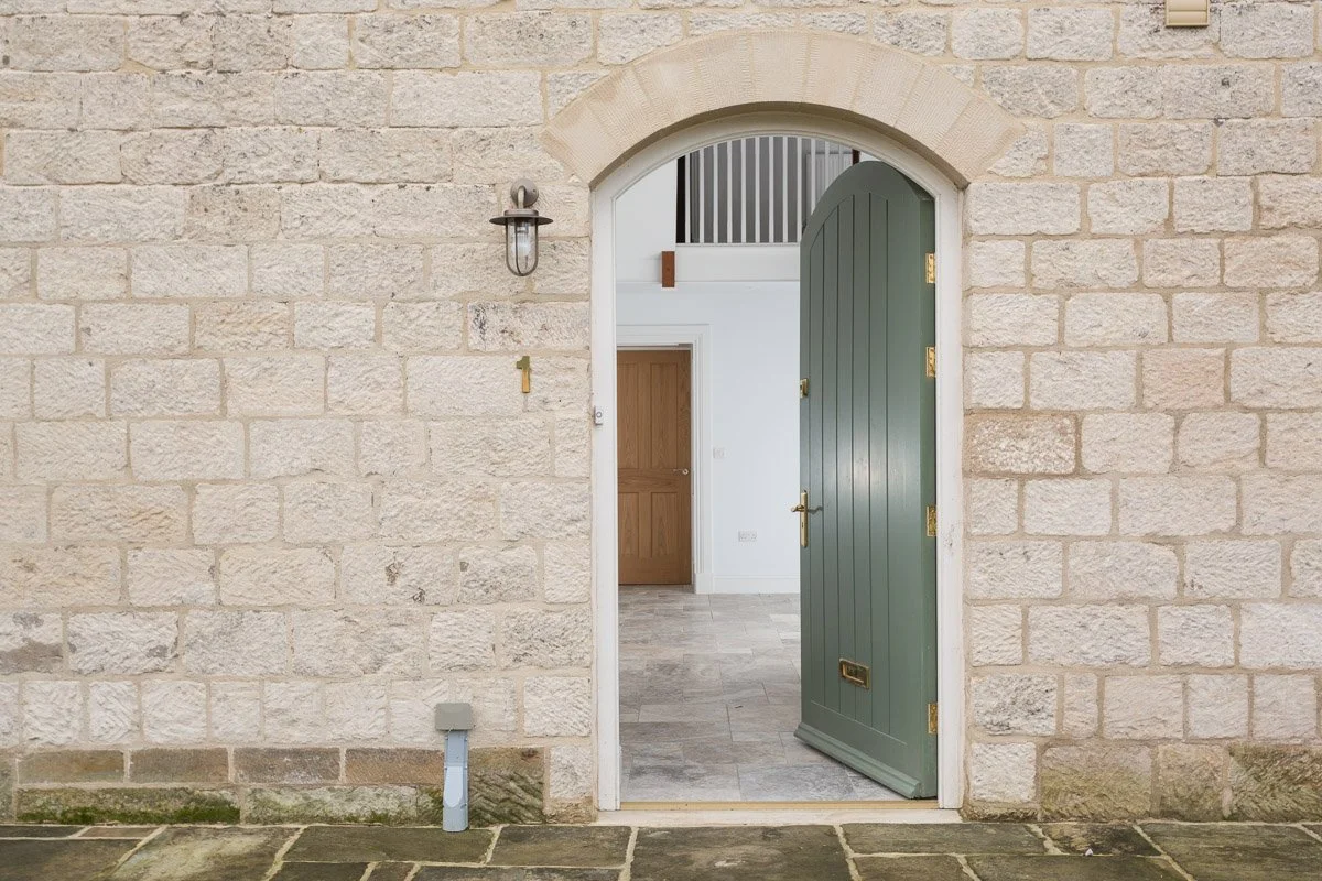 pale stone house with front door open looking into large entrance hallway