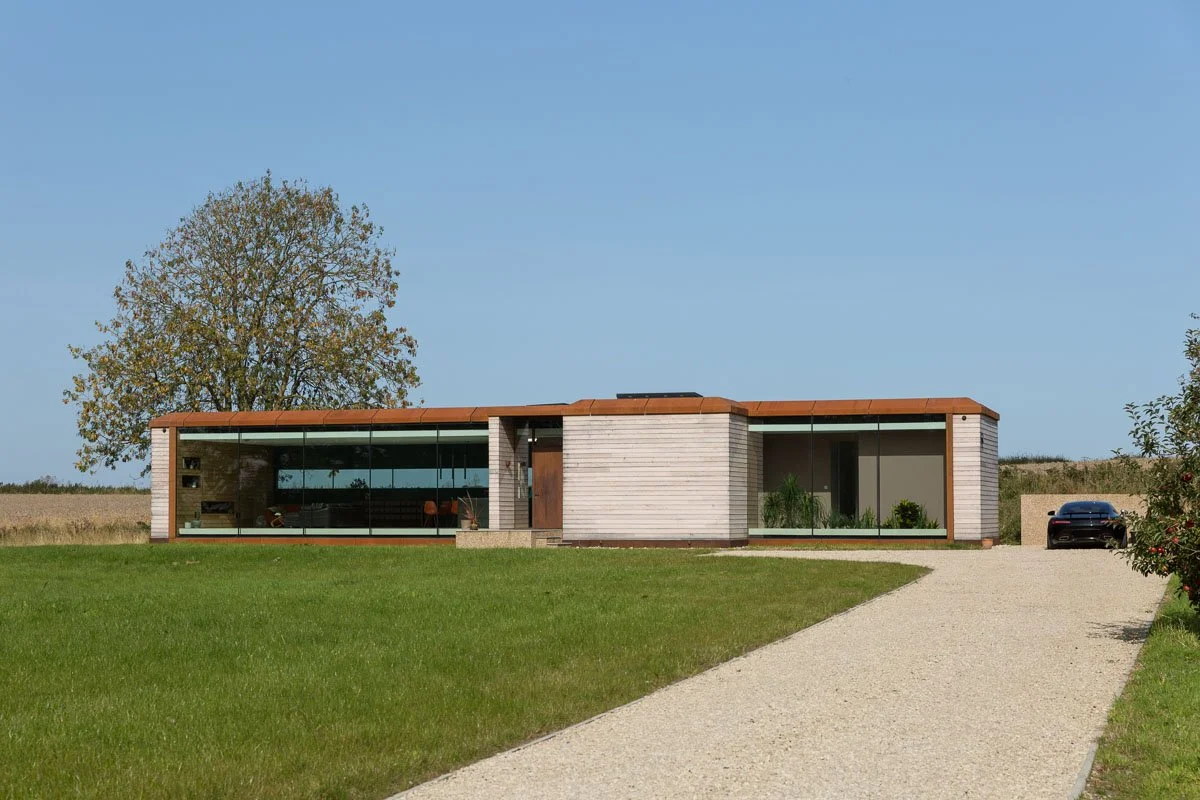 eco home with glass front long driveway and manicured lawn