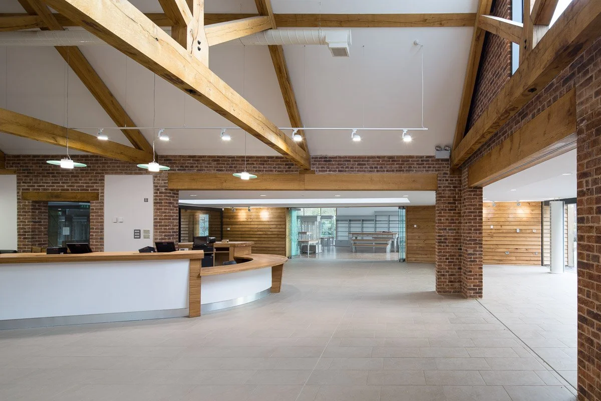 reception room, high beamed ceiling with pale tiled flooring, large curved white and wooden desk