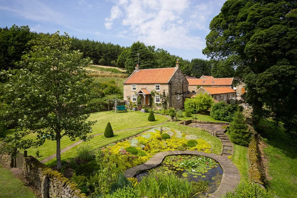 farmhouse with walled manicured garden and small pond 