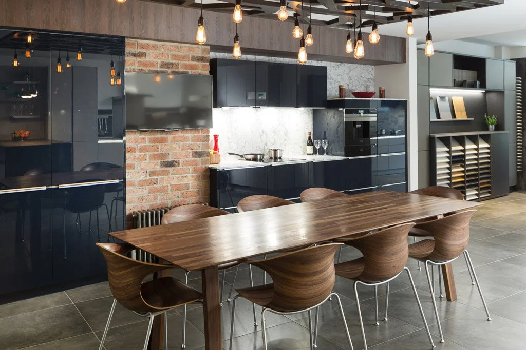 inside studio 35 kitchen design studio, dark kitchen units, wooden dining table and dark tile flooring