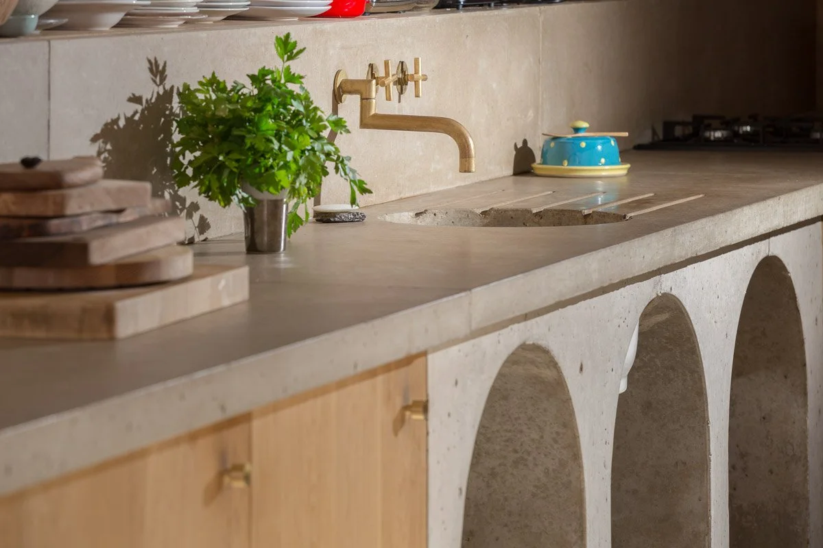 lifestyle of a concrete kitchen counter with brushed brass tap and circle sink  