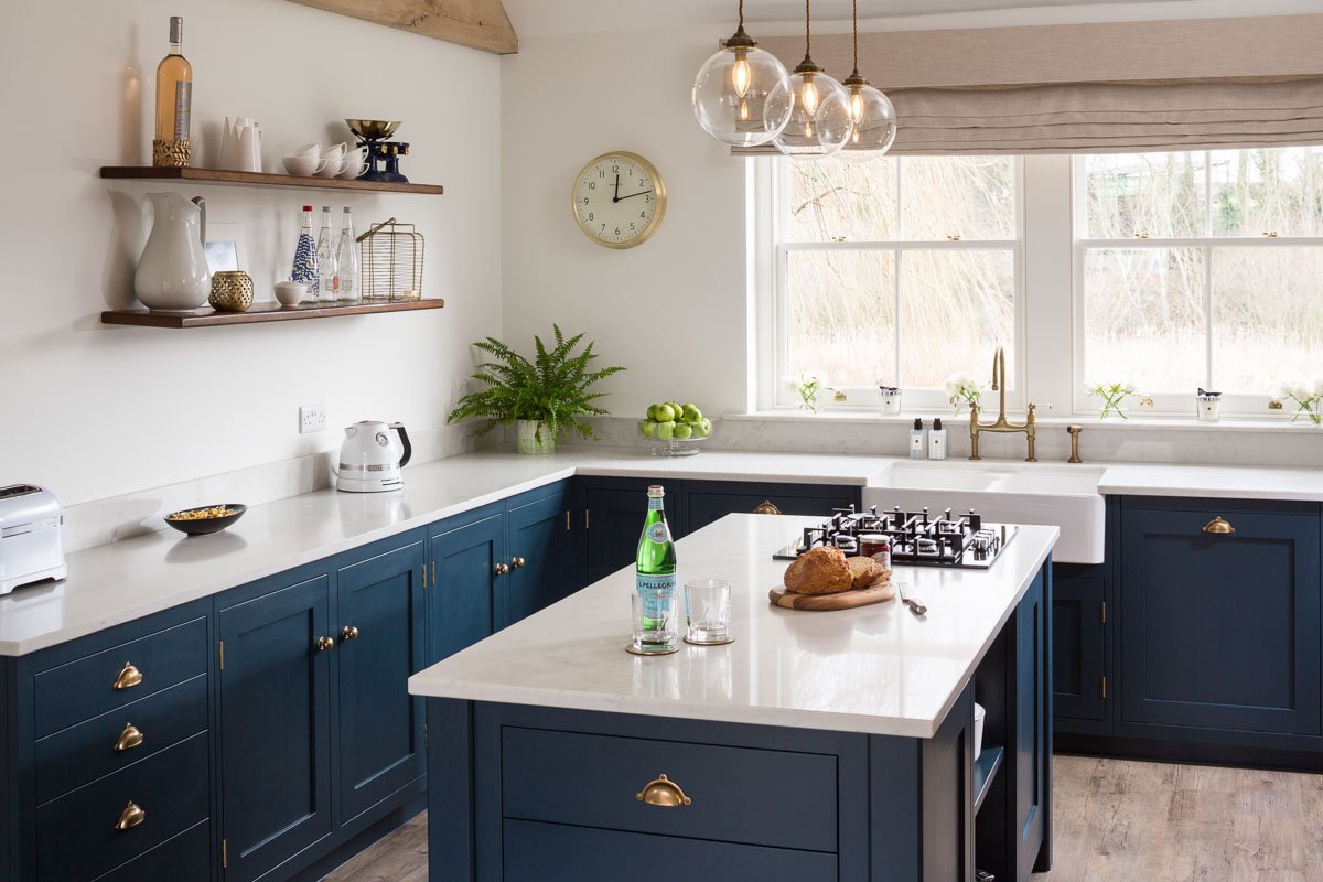 dark blue shaker style kitchen with white counter tops and island 