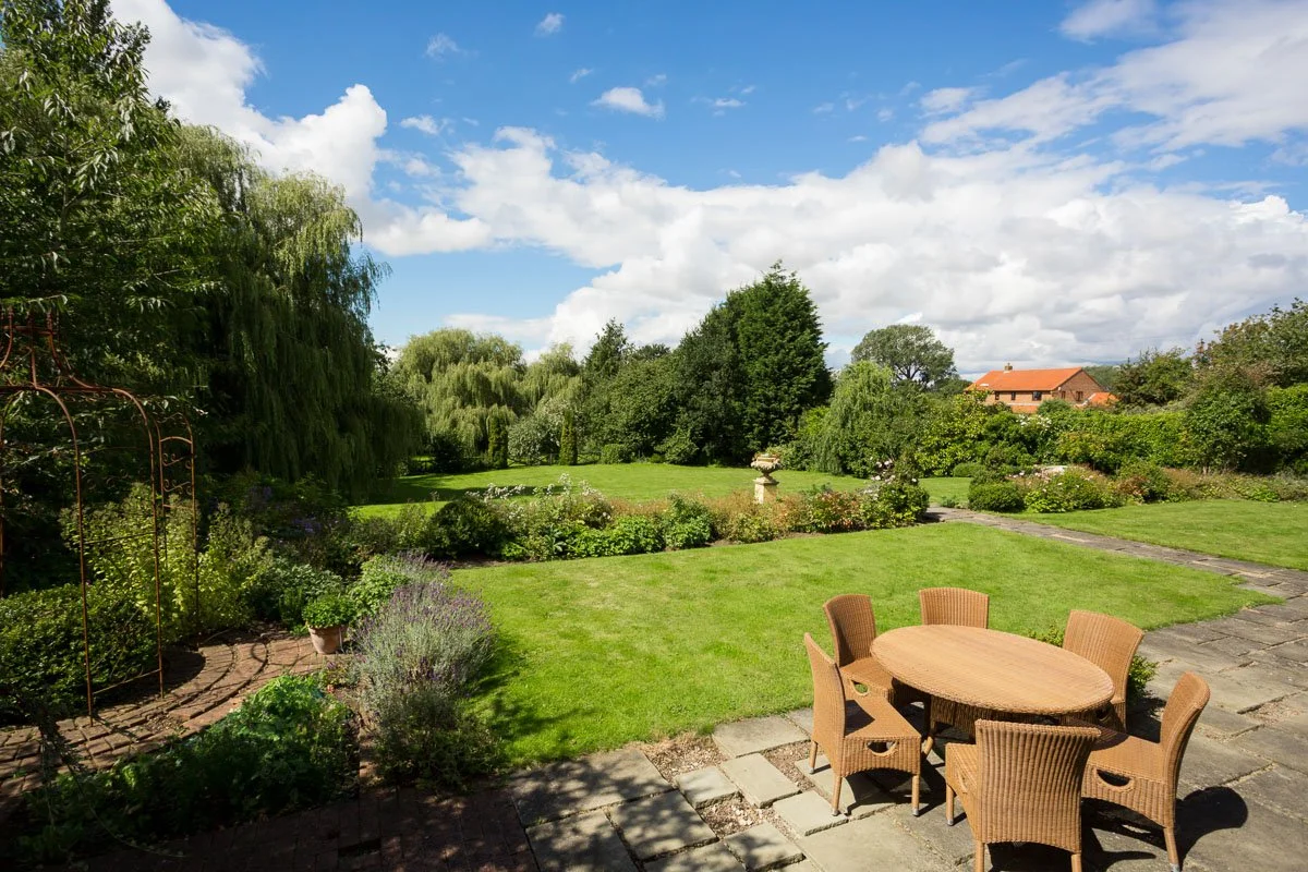 large tiered manicured lawn with flagstone patio and wicker furniture 