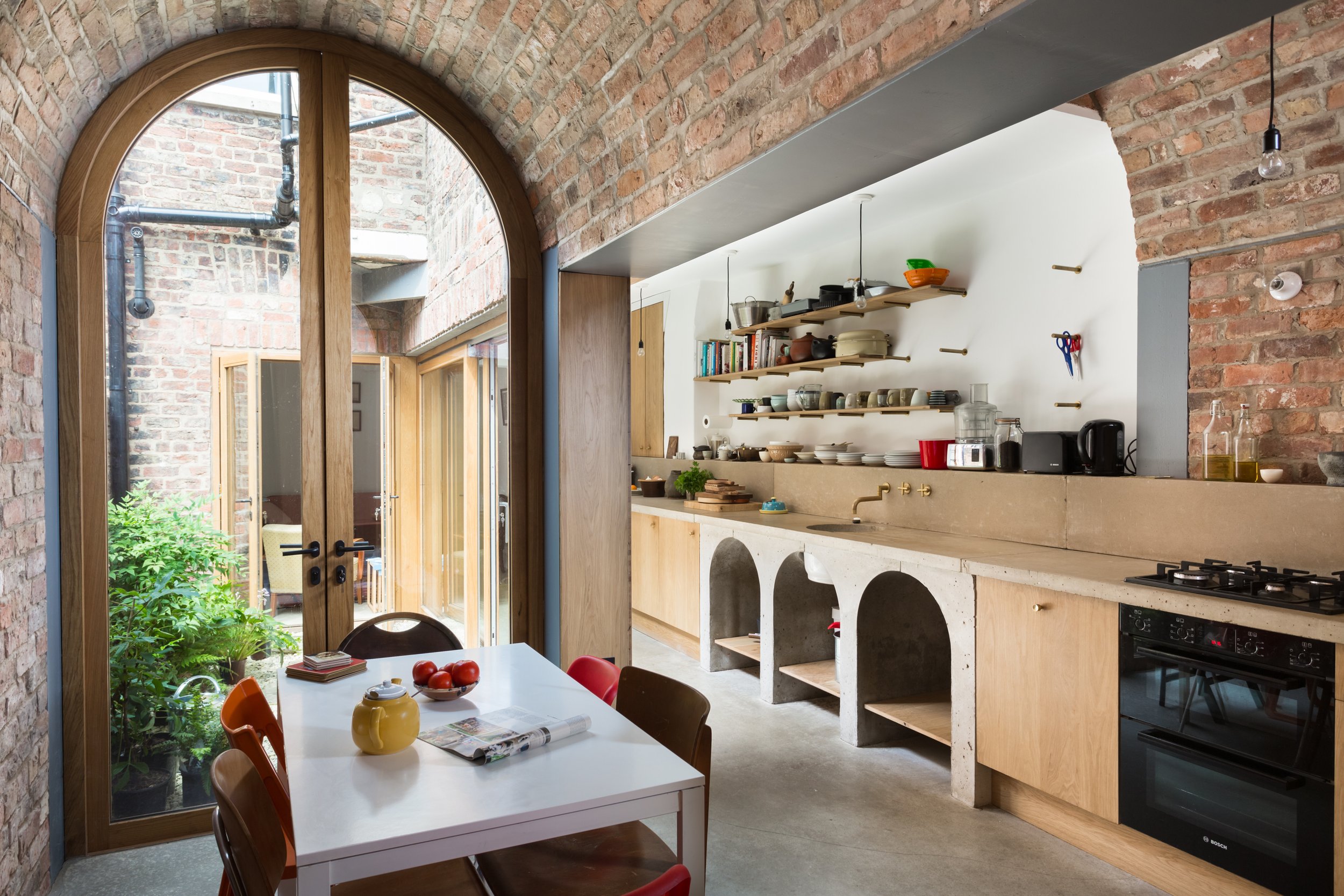 modern kitchen extension with concrete flooring and countertops with a brick barrelled roof