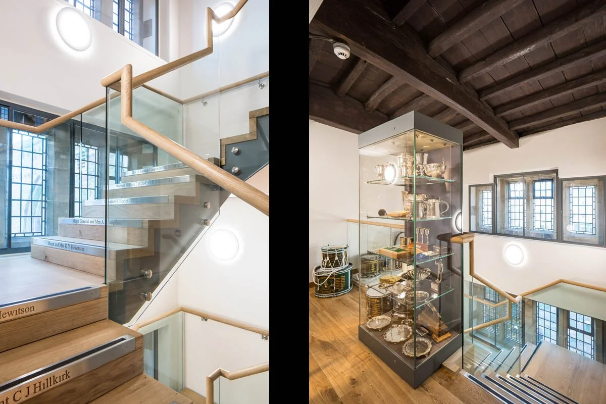 left: wooden staircase leading up with glass banister and words inscribed on the facing of the stairs, right: on the landing, large glass unit with historical artefacts 