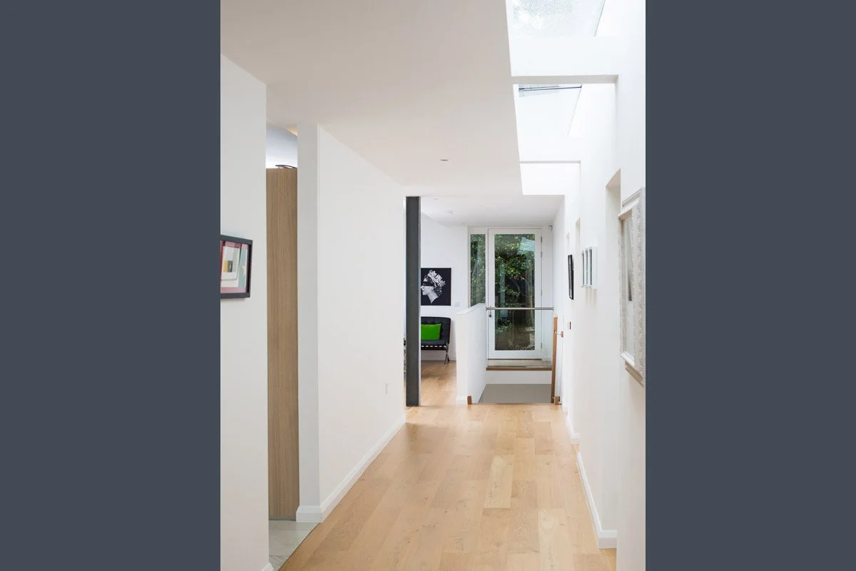 portrait image of modern hallway with wooden flooring, white walls and skylights