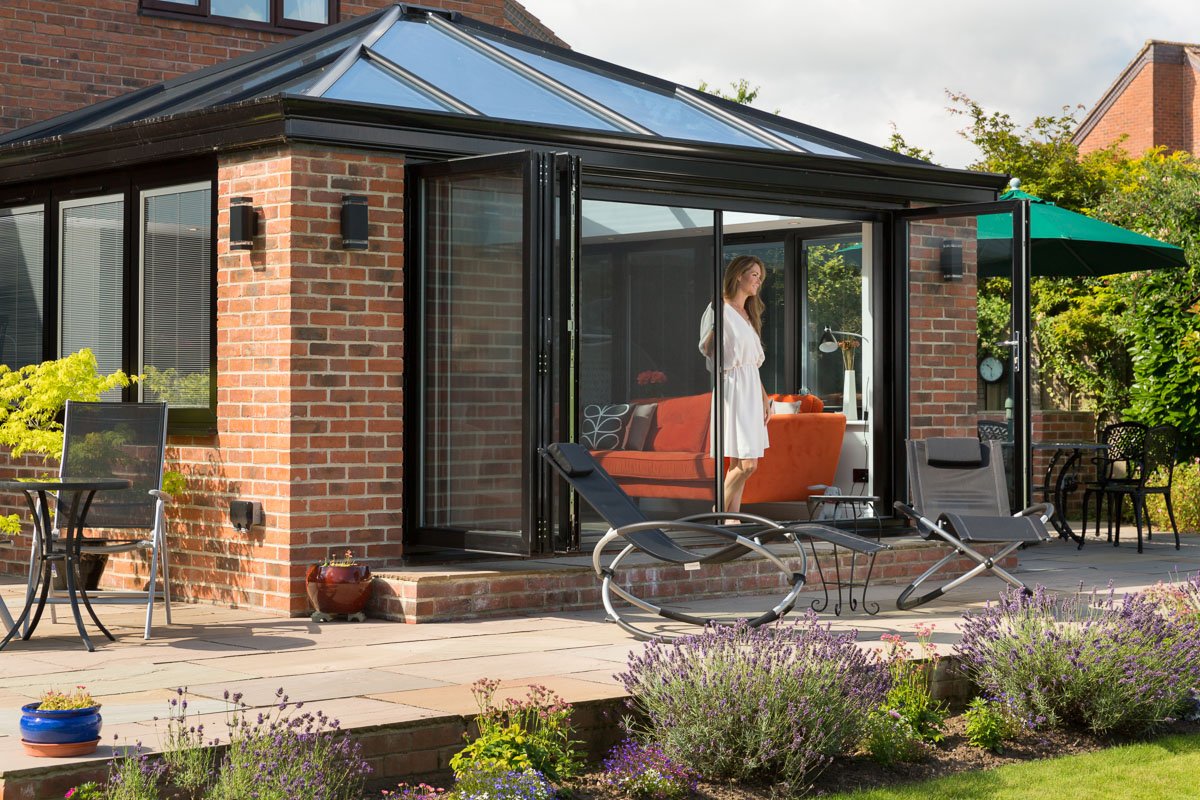 still image from a video campaign on sliding bug screens, view from across garden of woman pushing open bug screen