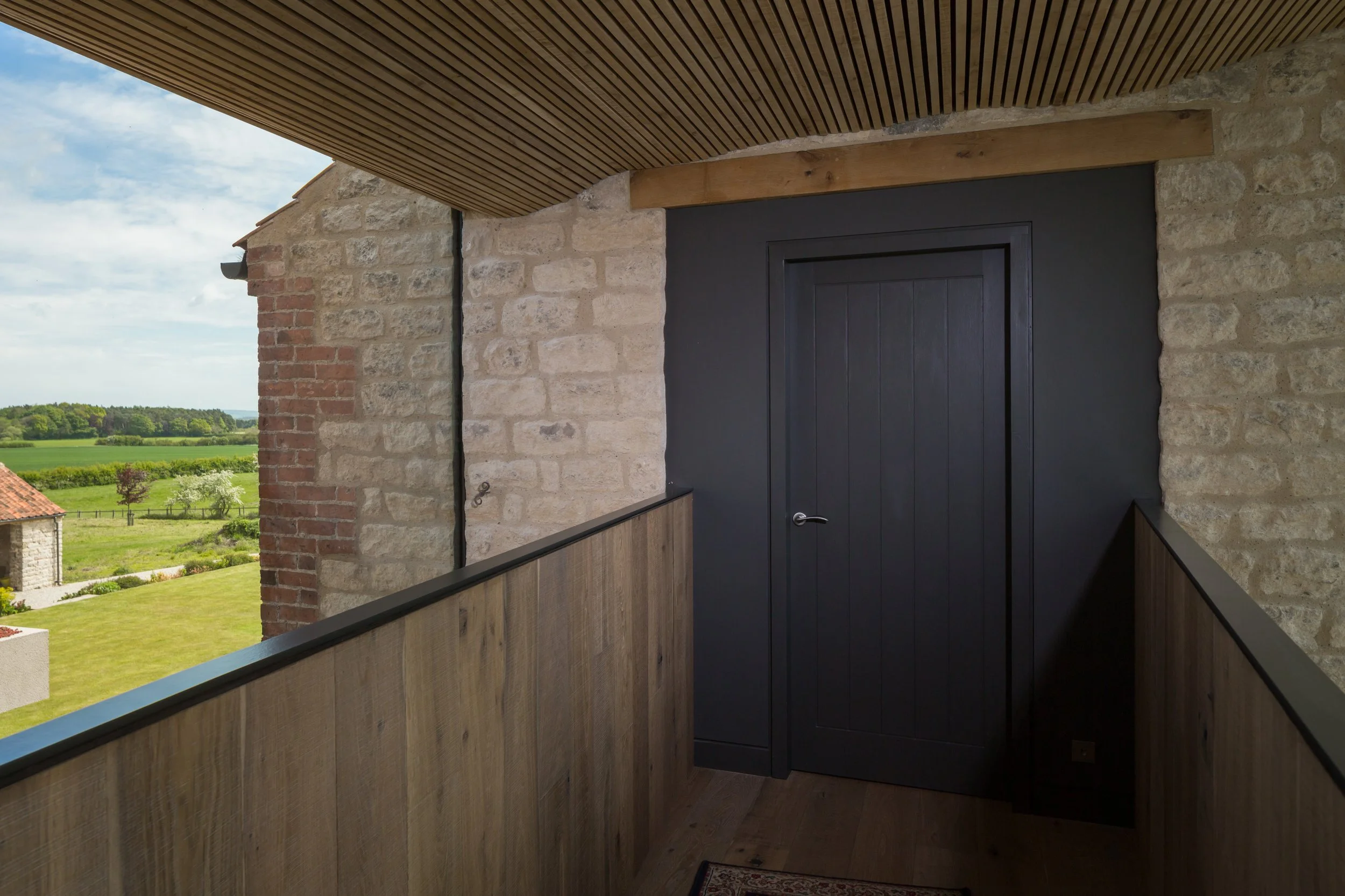 first floor sky walk in residential house with timber battened ceiling and frame-less glazing