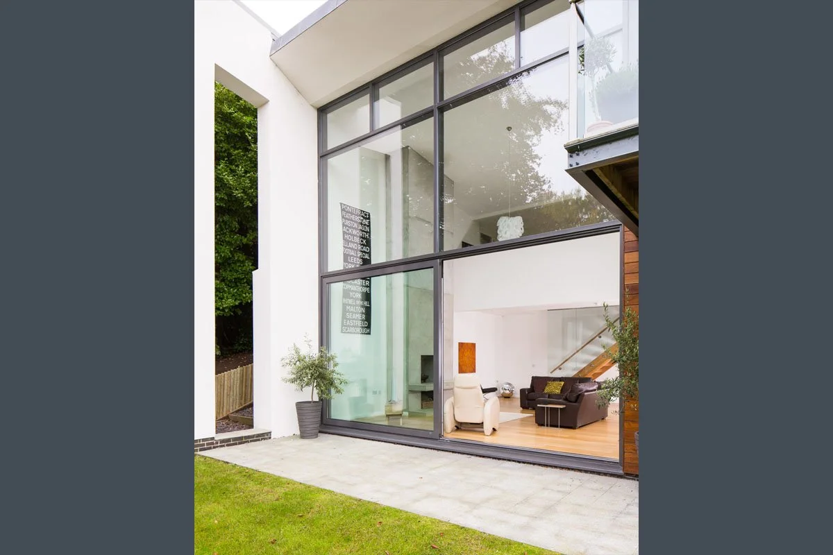 portrait image of architect design house with full height glass wall looking into living room