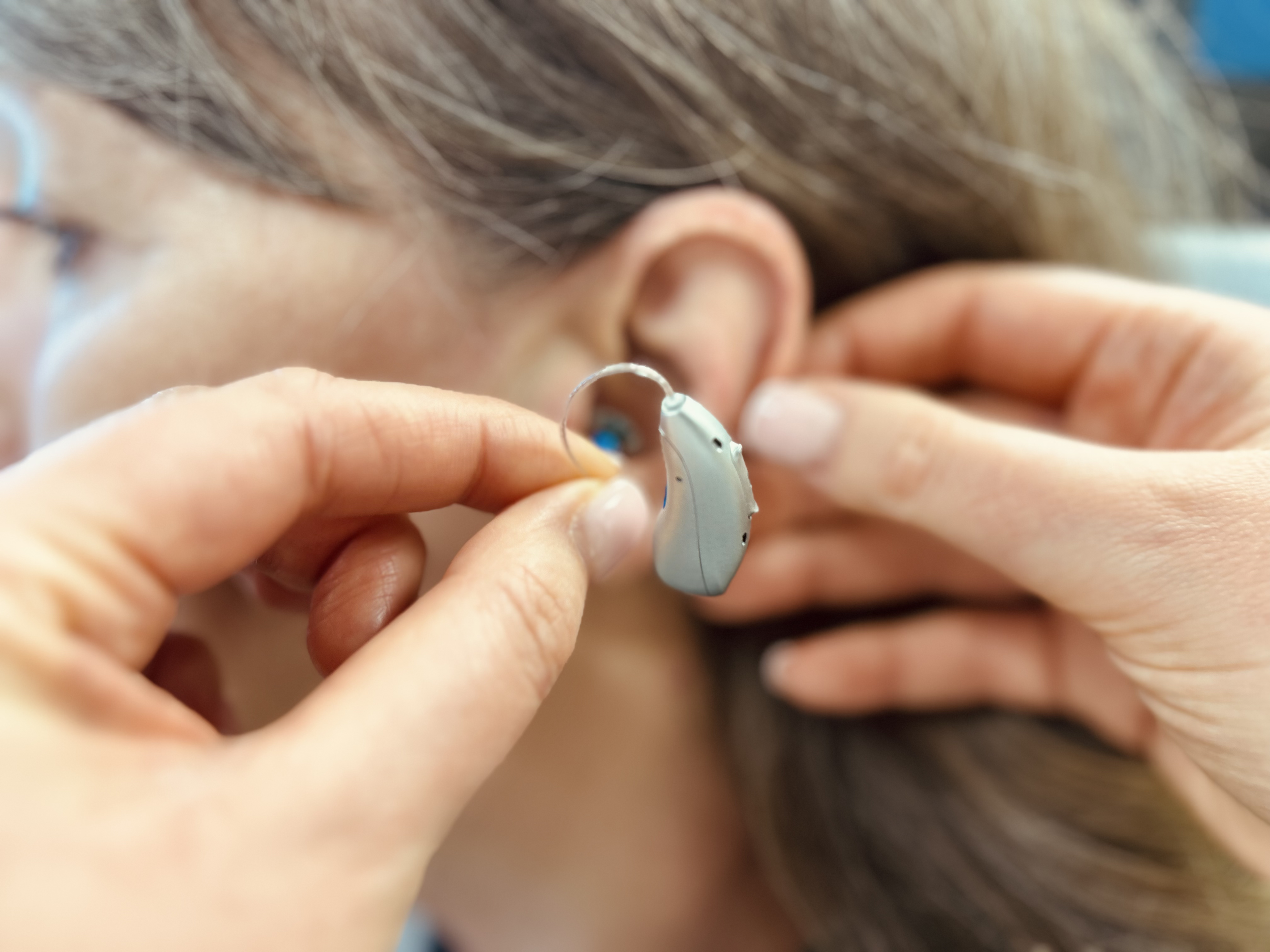 a modern hearing aid being fitted to the ear of a woman.