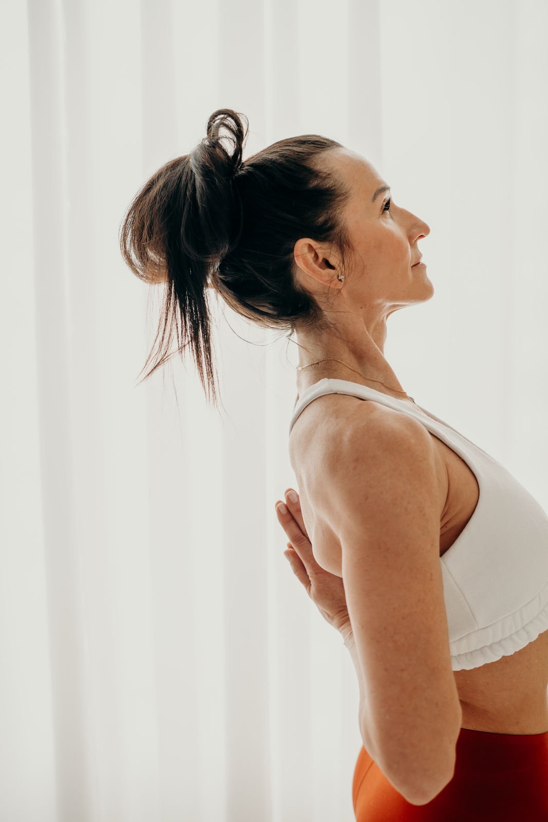 Frau beim Yoga, die eine Rückbeuge macht, vor weißem Hintergrund.