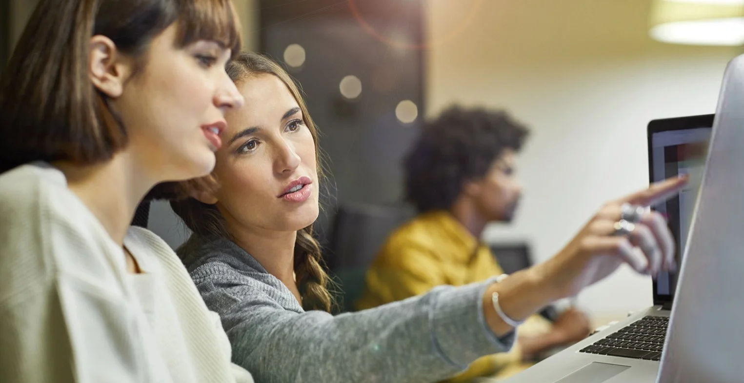 Women working together at a computer in an office setting