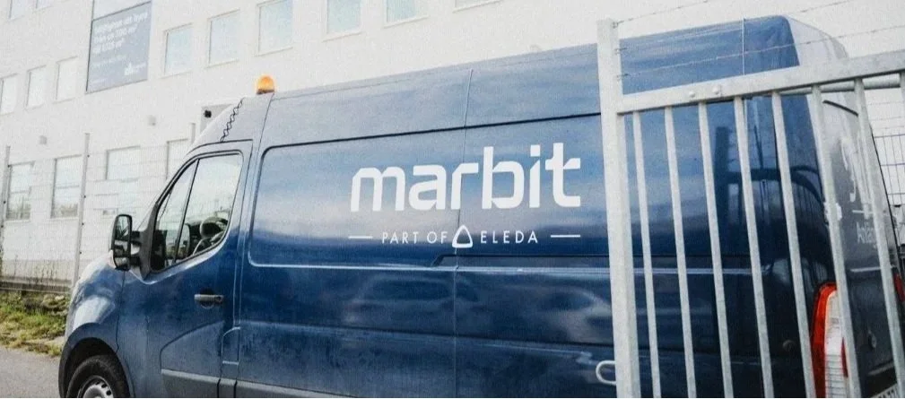 A blue delivery van with the logo 'marbit' and the tagline 'Part of Eleda' parked outside a building.