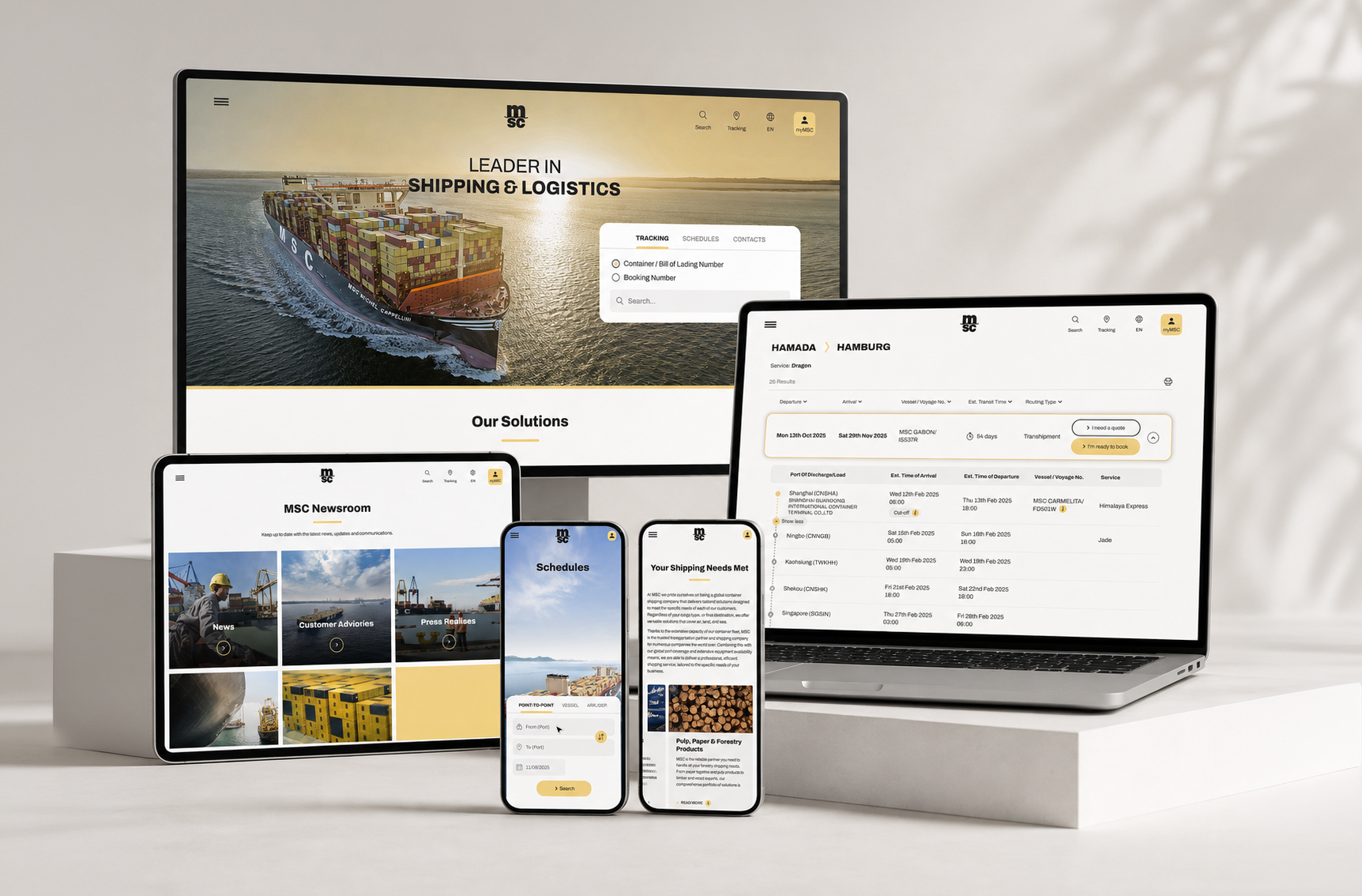 Displays multiple electronic devices showcasing a logistics company's website and mobile app, including a large monitor, a laptop, a tablet, and two smartphones, all on a white table with a light background.