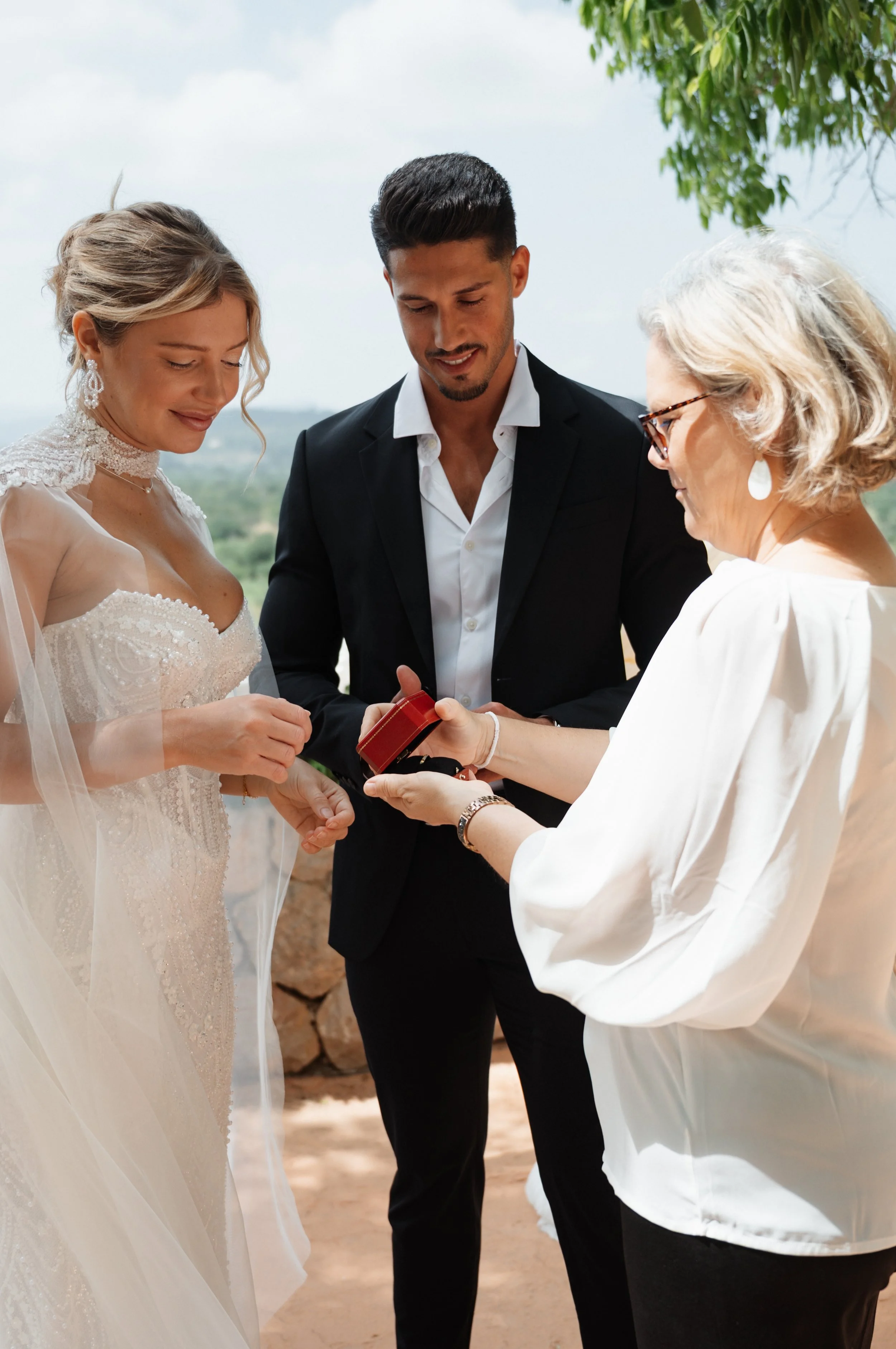 Ein Brautpaar bei der Hochzeitszeremonie, das von seiner Hochzeitsplanerin Alexandra Freudenreich ihre Vows-Liebesversprechen erhält, im Freien vor der freien Trauung bei Traumwetter auf der Finca Son Termens auf Mallorca.