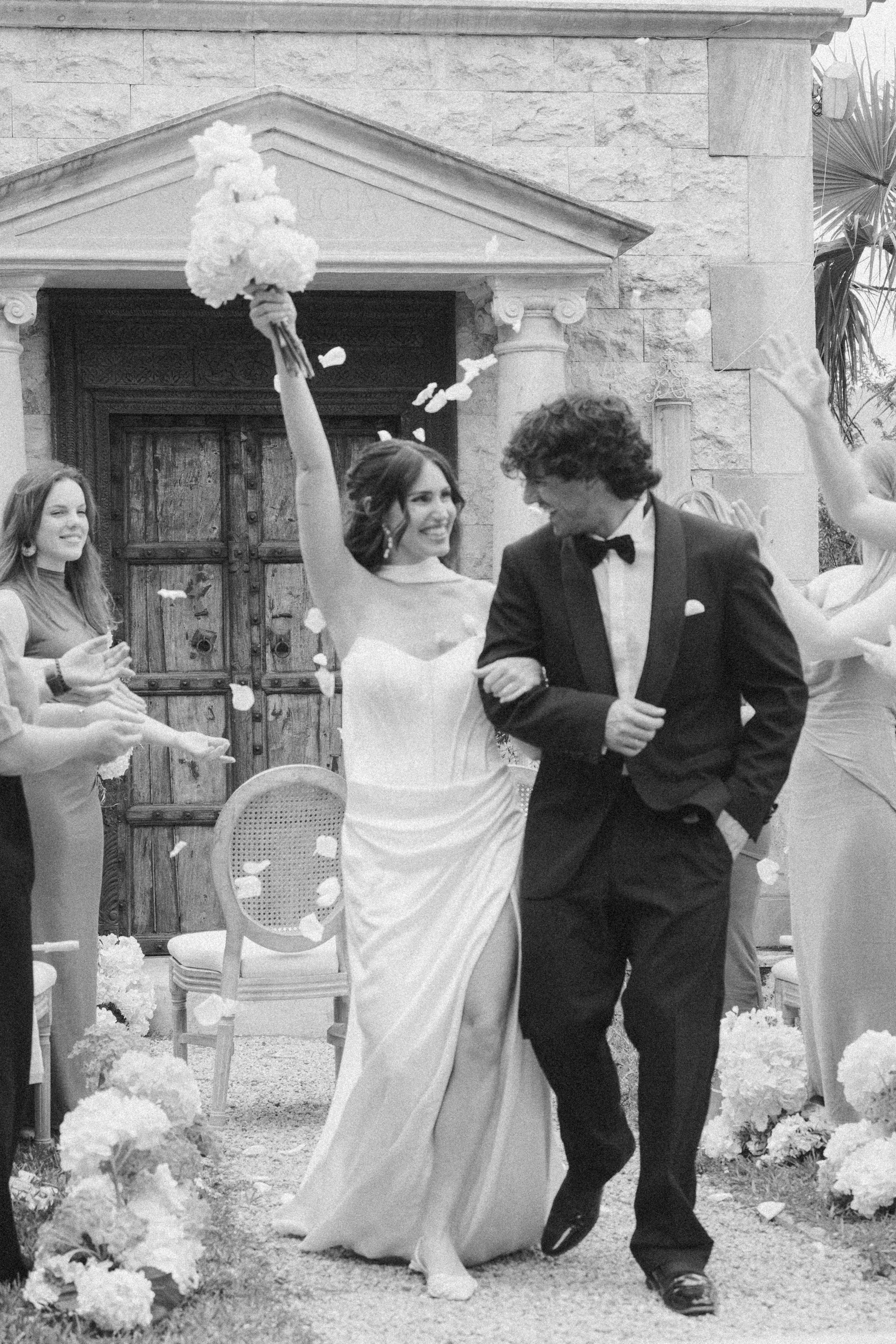 Ein Brautpaar tanzt während einer Hochzeit im Freien, umgeben von Blumen und Gästen.