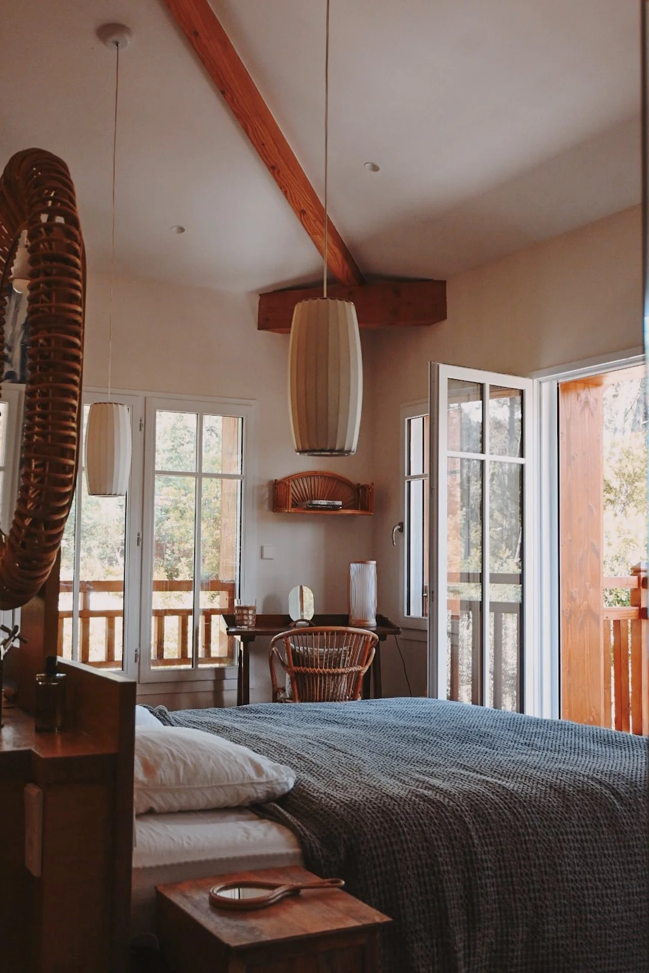 Suite privative avec lit double et porte-fenêtre ouvrant sur un balcon en bois — hébergement de charme d'une retraite yoga et surf au Cap Ferret