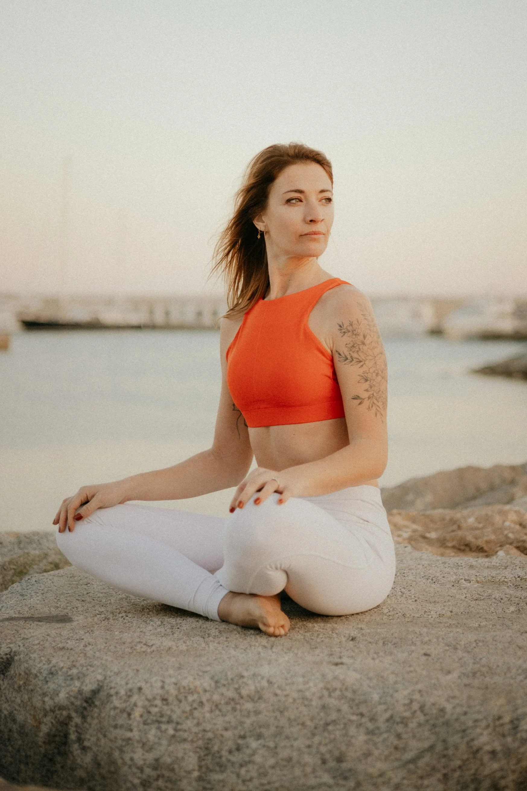 Jenny De Quenetain, professeure de yoga, assise en méditation sur un rocher face à la mer au crépuscule — retraite yoga bord de mer en Baie de Somme