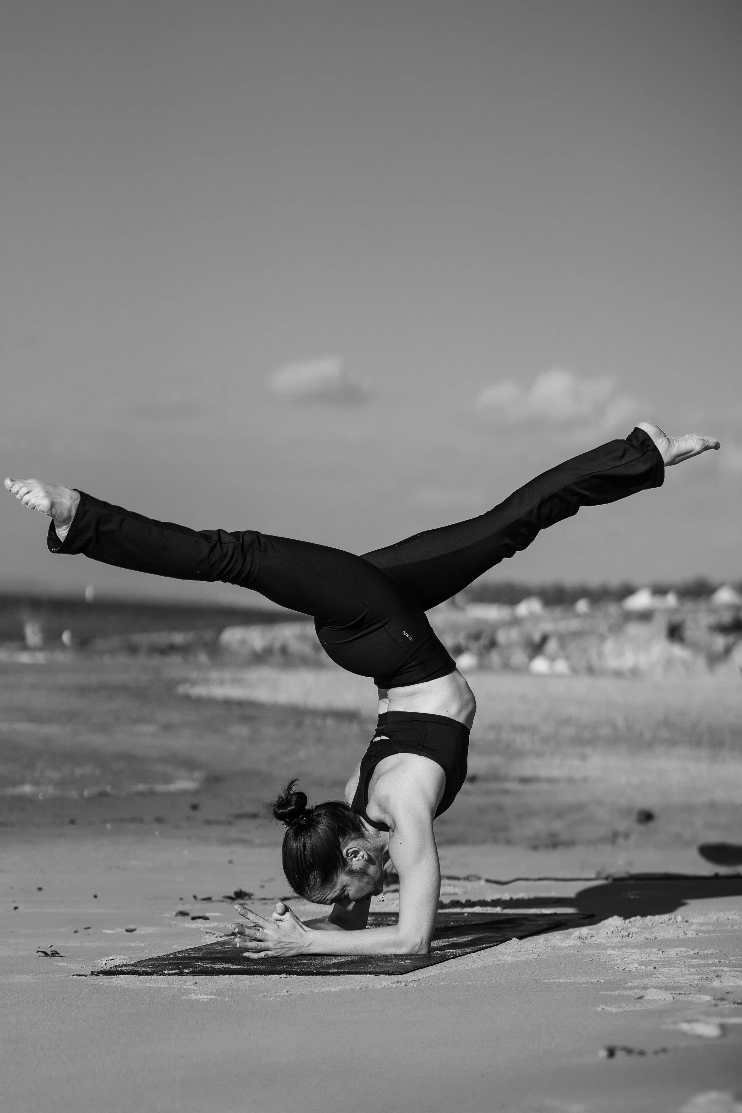 Femme en posture inversée avancée sur la plage en noir et blanc, retraite de yoga Sud-Ouest nouvel an Landes