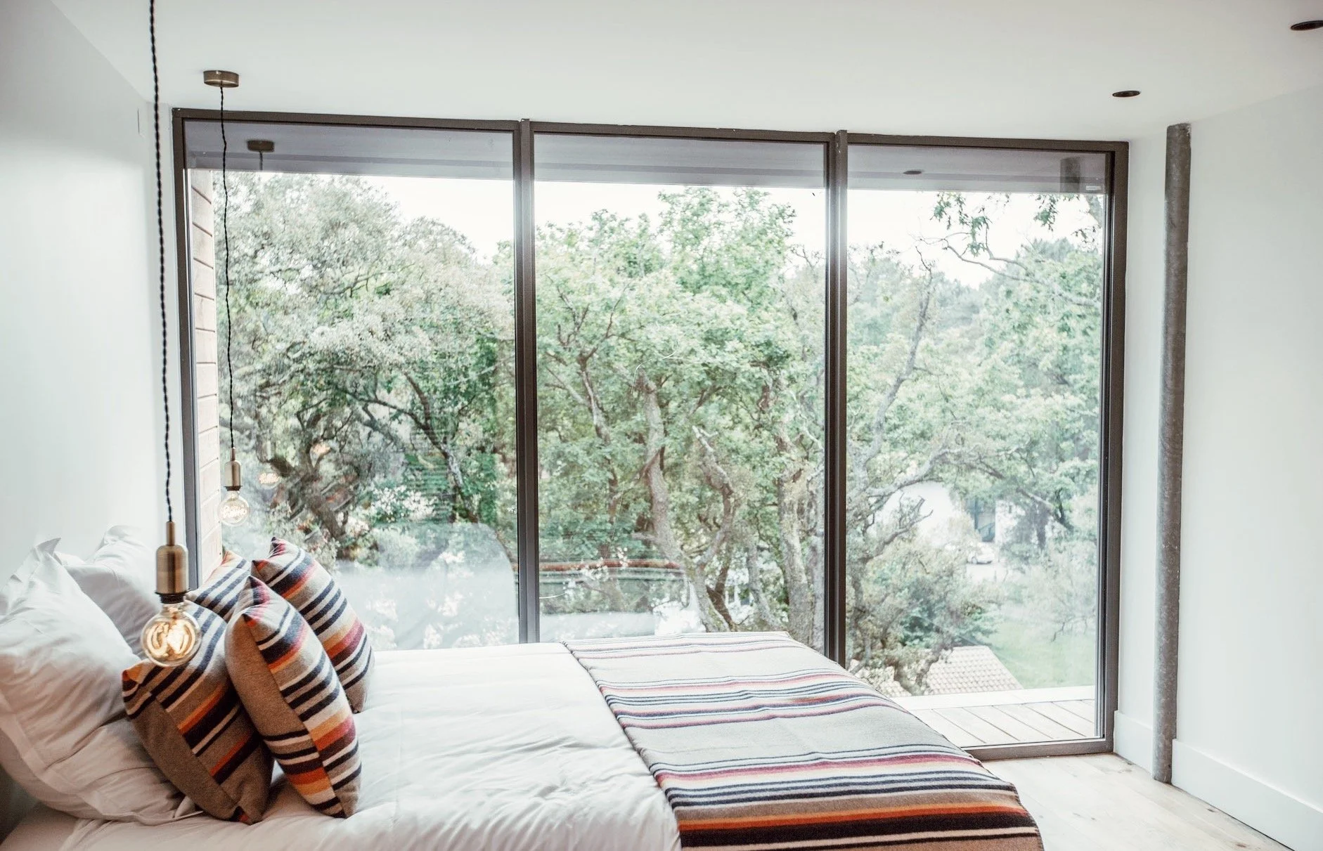 Chambre cosy avec linge de lit artisanal et vue sur la nature – un cocon de confort et de douceur pour se régénérer entre deux pratiques de yoga.