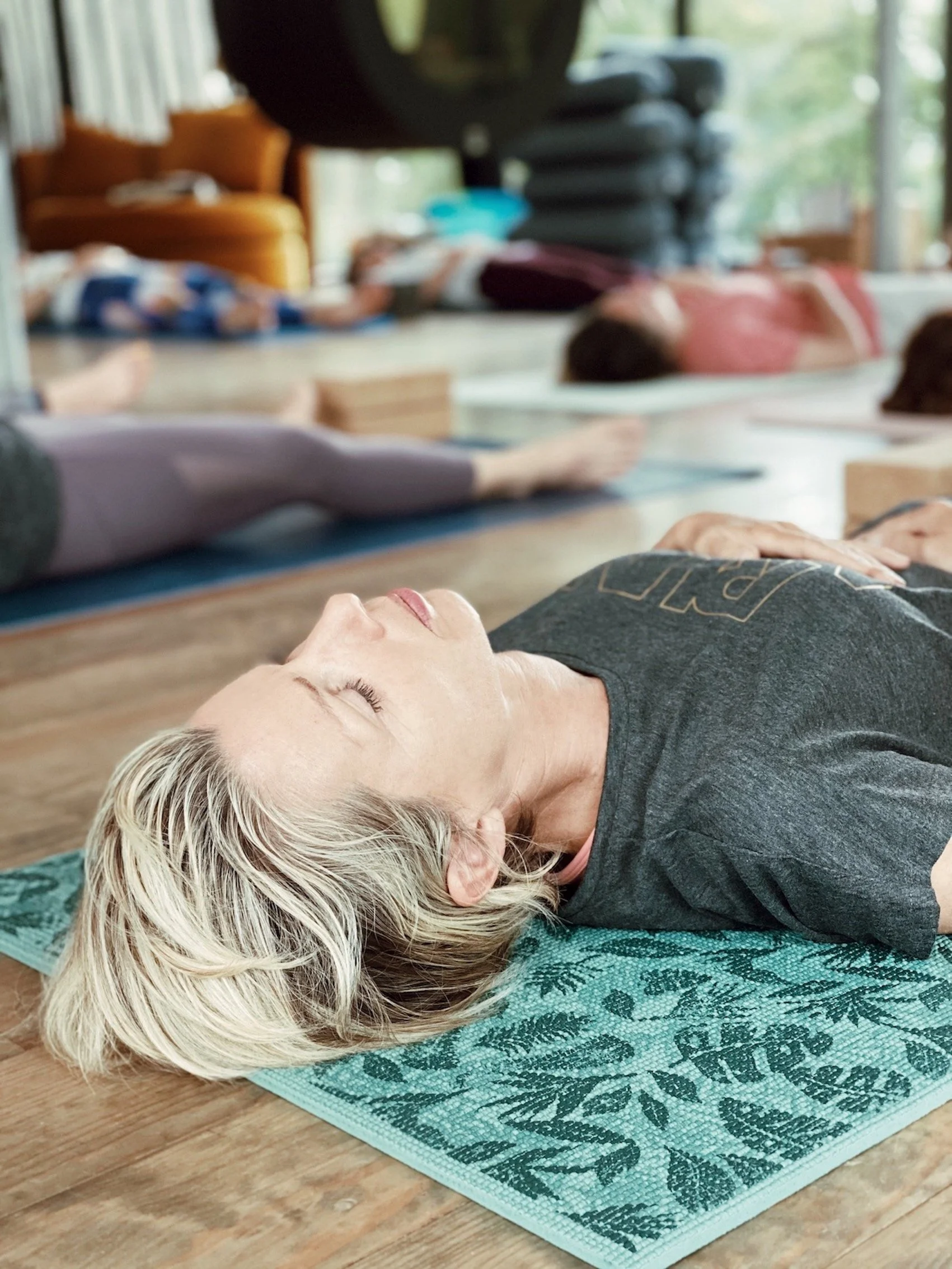 Femme en posture de savasana lors d'un cours de yoga collectif, retraite bien-être nouvel an Hossegor Landes