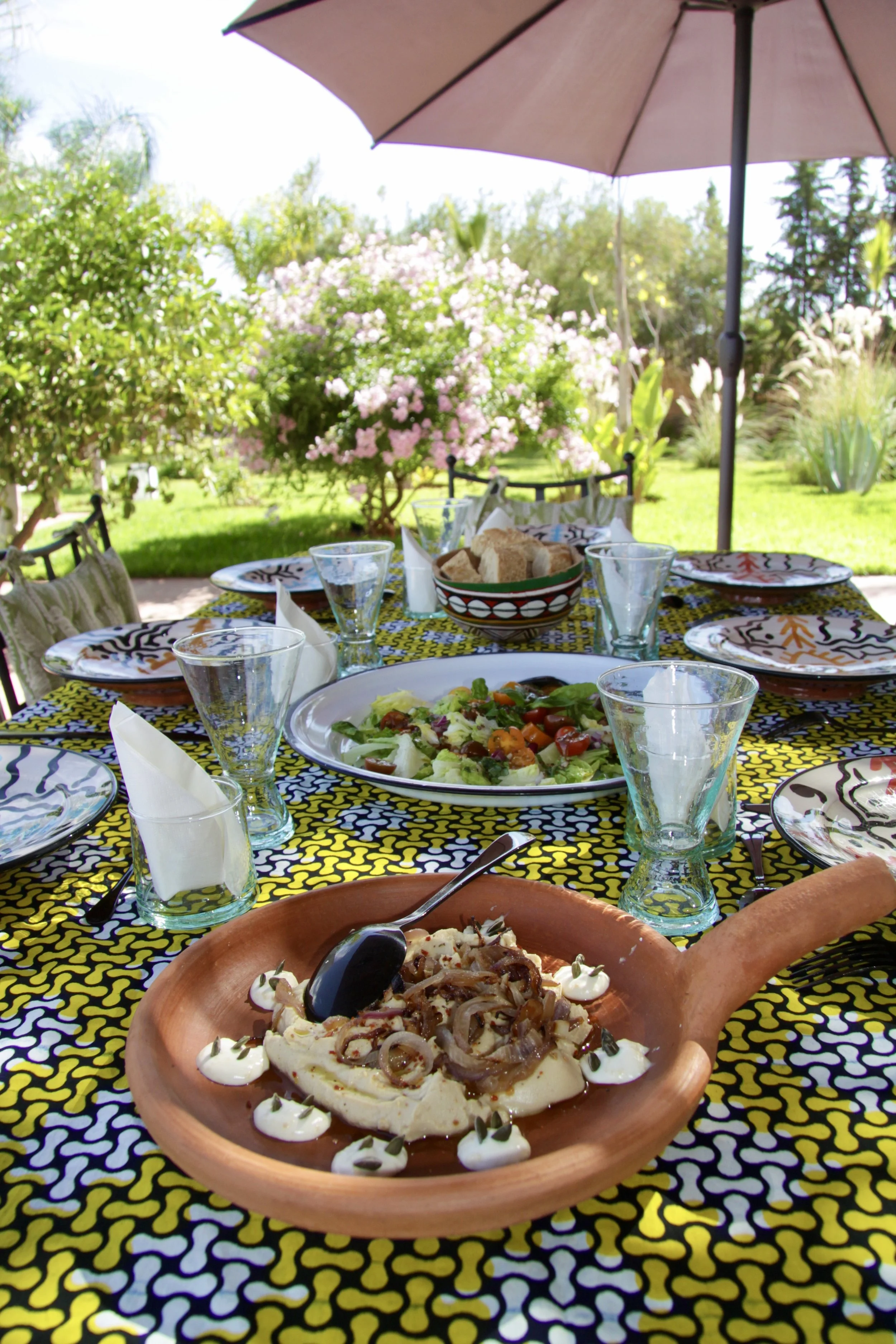 Table dressée en plein air dans le jardin du riad — repas végétarien marocain retraite yoga arrière-pays Marrakech
