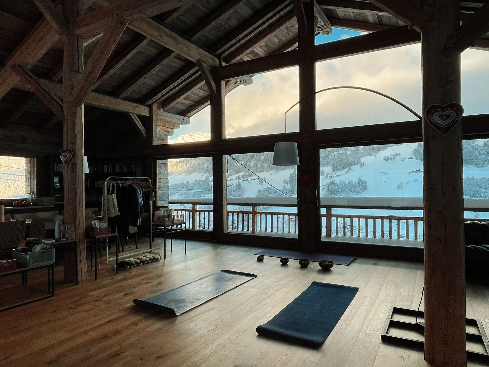 Retraite yoga dans un chalet en bois avec vue sur la montagne enneigée, tapis de yoga, bols chantants, dans les Alpes