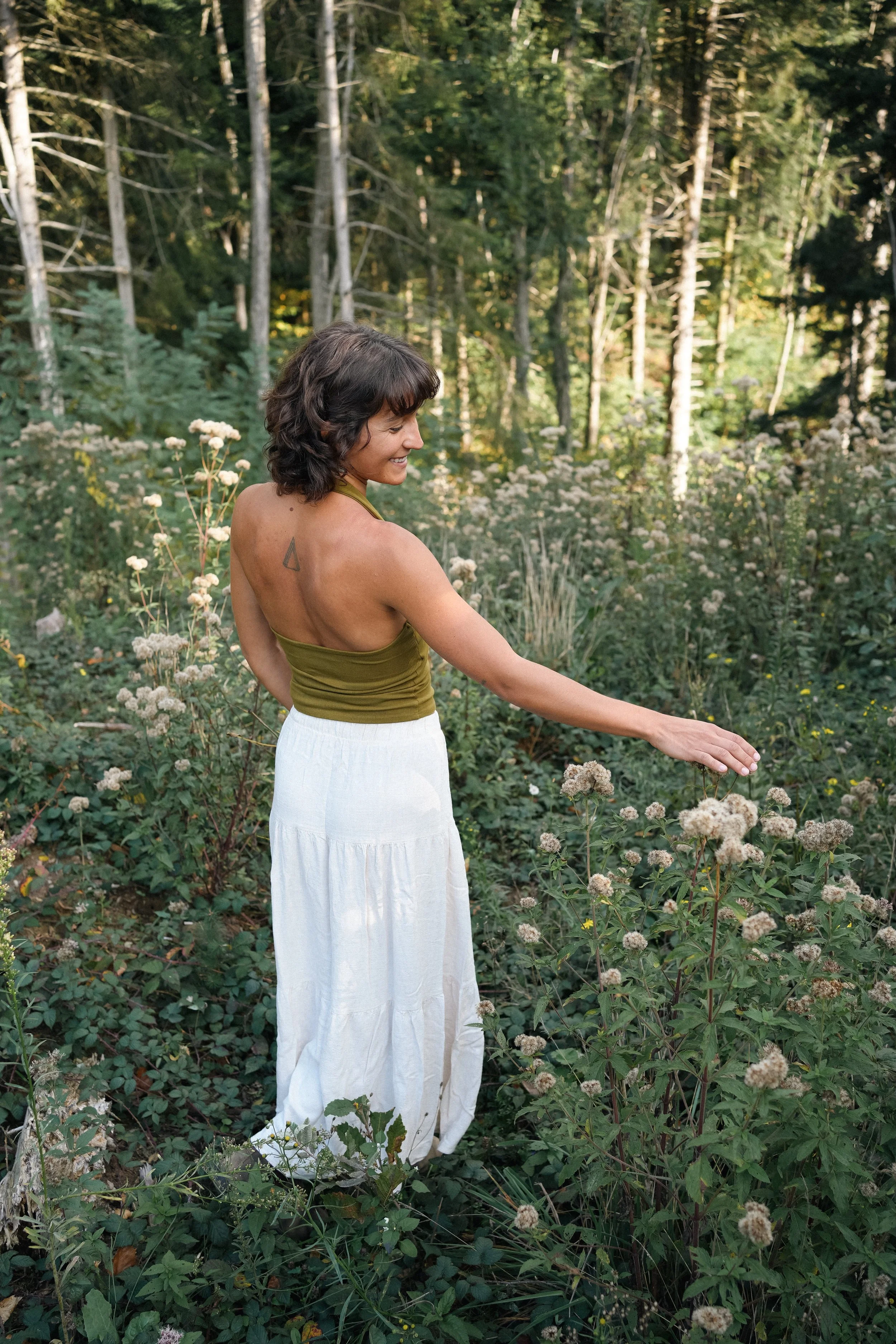 Femme en robe blanche explorant un champ de fleurs sauvages - séjour reconnexion à la nature