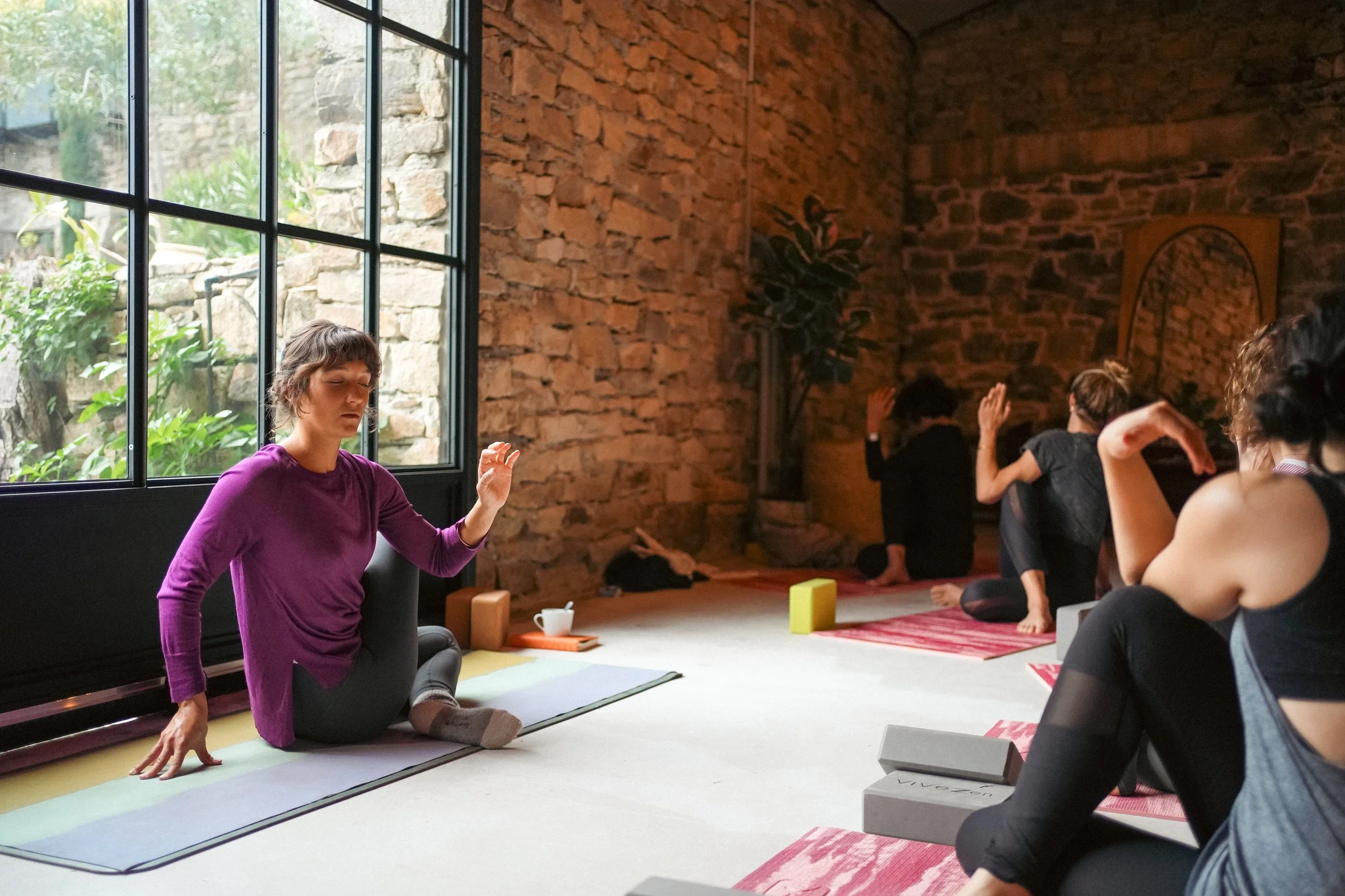 Séance de yoga en conscience dans un cocon de pierre et de lumière, au cœur de la nature, lors de la retraite "Sagesse des femmes" dans le Sud de la France.
