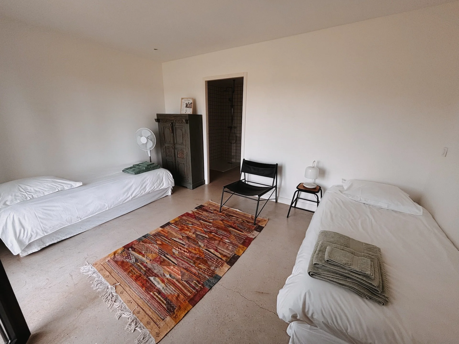 Chambre simple lumineuse avec tapis kilim et armoire ancienne — hébergement retraite yoga chamanisme Solterre proche de Paris 2026