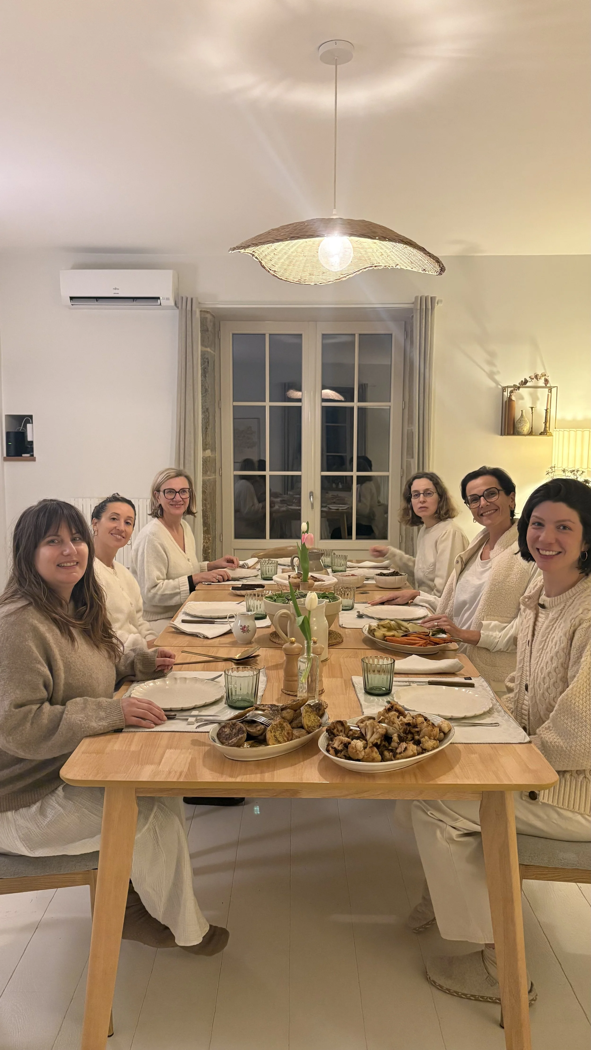 Six femmes souriantes autour d'un dîner végétarien à la bougie — retraite yoga bien-être en petit groupe Bourgogne automne