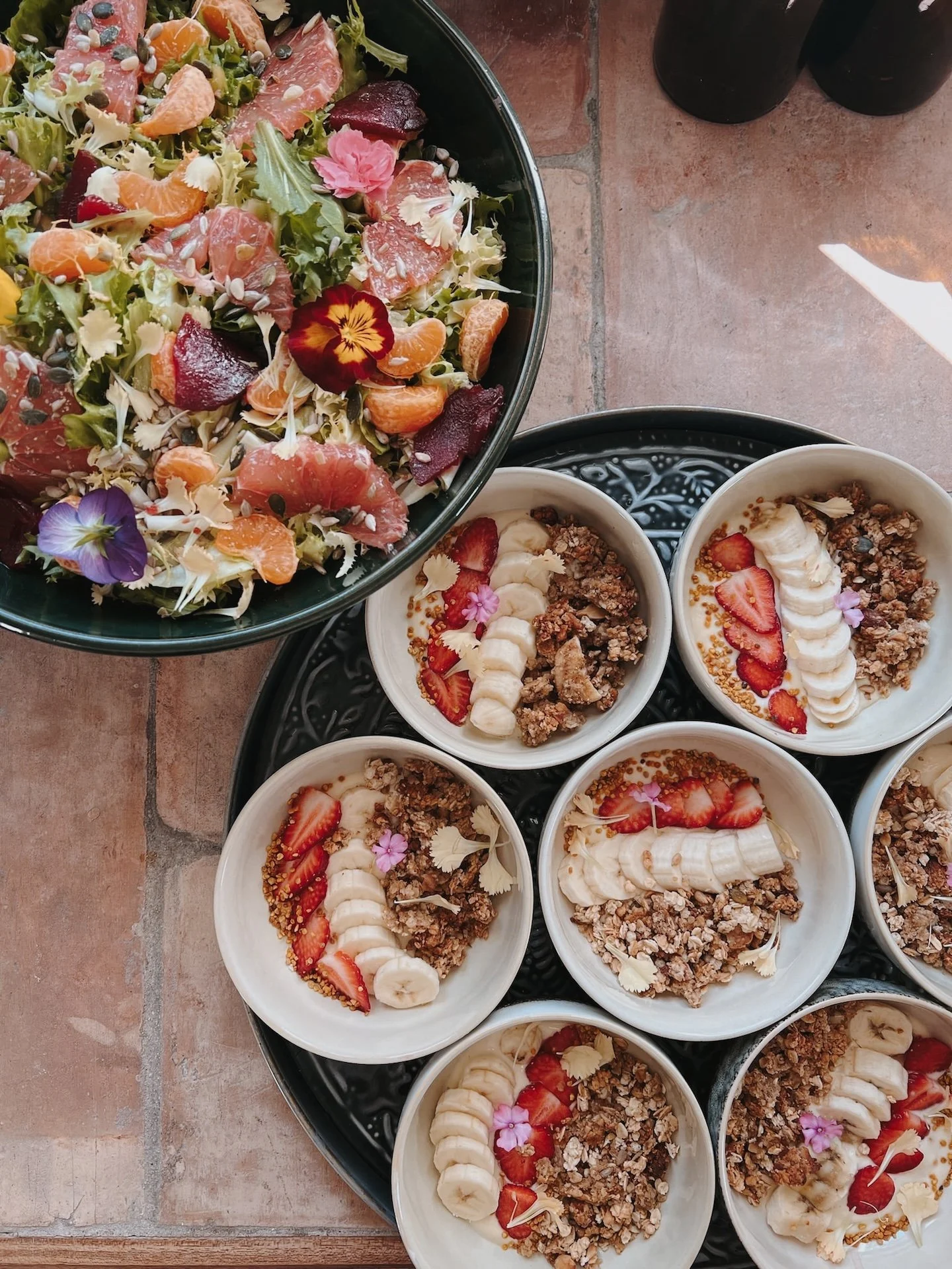Salade d'agrumes et betterave entourée de bowls de granola aux fraises — petit-déjeuner gourmand et végétarien d'une retraite yoga et surf