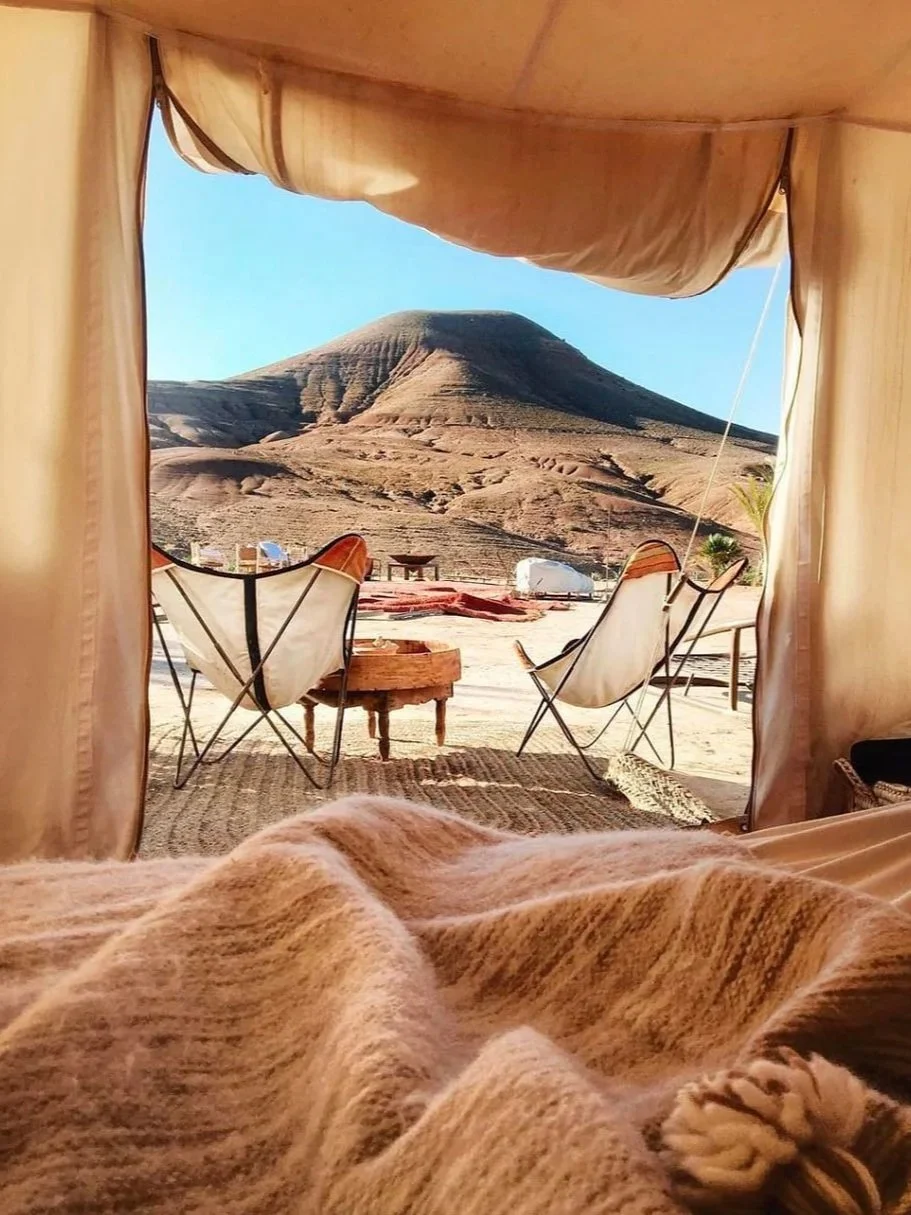 Vue depuis l'intérieur d'une tente safari sur les dunes rocheuses d'Agafay — nuit glamping désert retraite yoga Maroc novembre