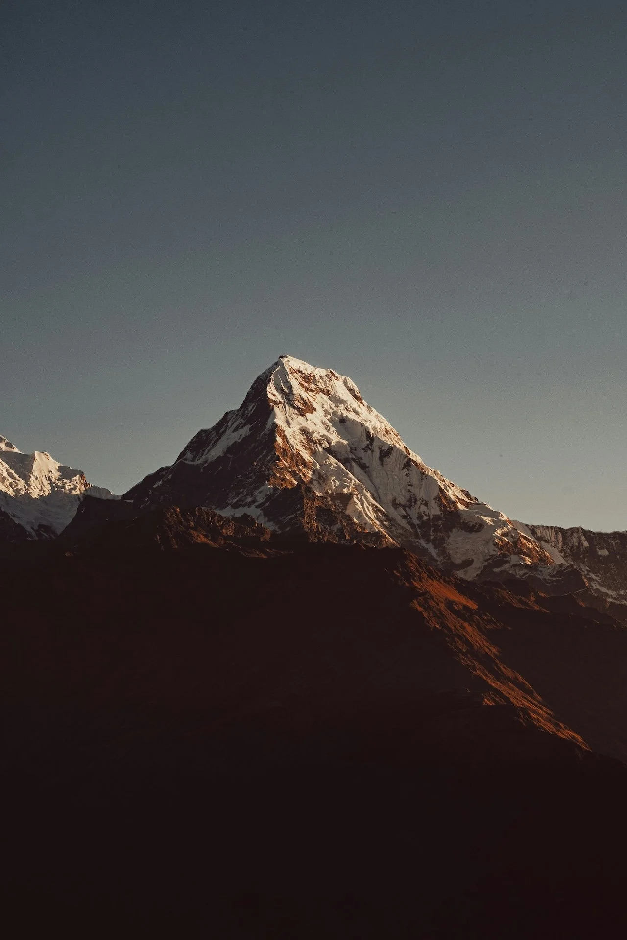 Sommet enneigé de l'Himalaya au crépuscule, ciel sombre et lumière rasante sur la montagne — voyage spirituel au Népal