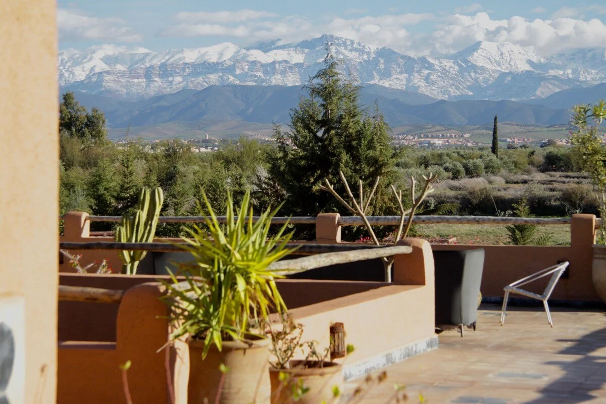Vue panoramique sur l'Atlas enneigé depuis une terrasse — retraite yoga arrière-pays Marrakech novembre 2026