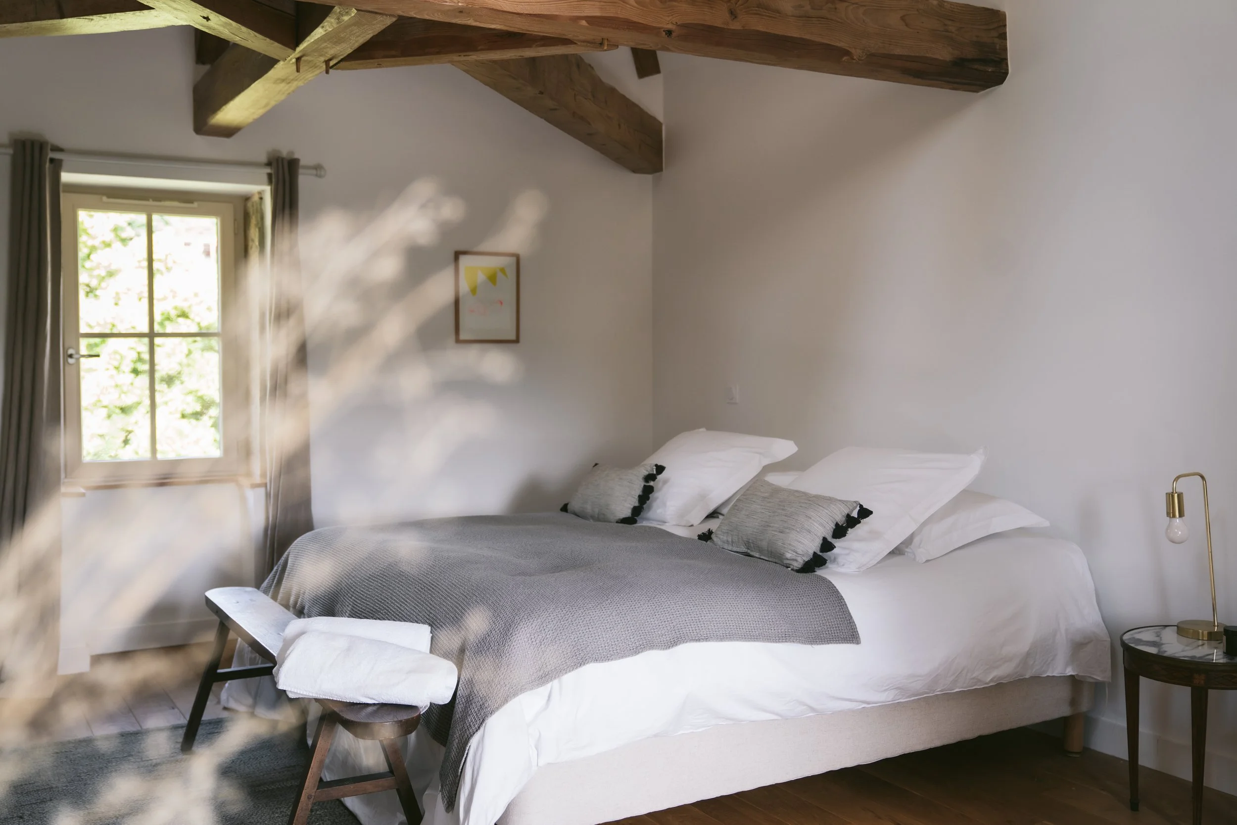 Chambre rustique avec poutres apparentes et literie douce — hébergement authentique retraite yoga Bourgogne automne