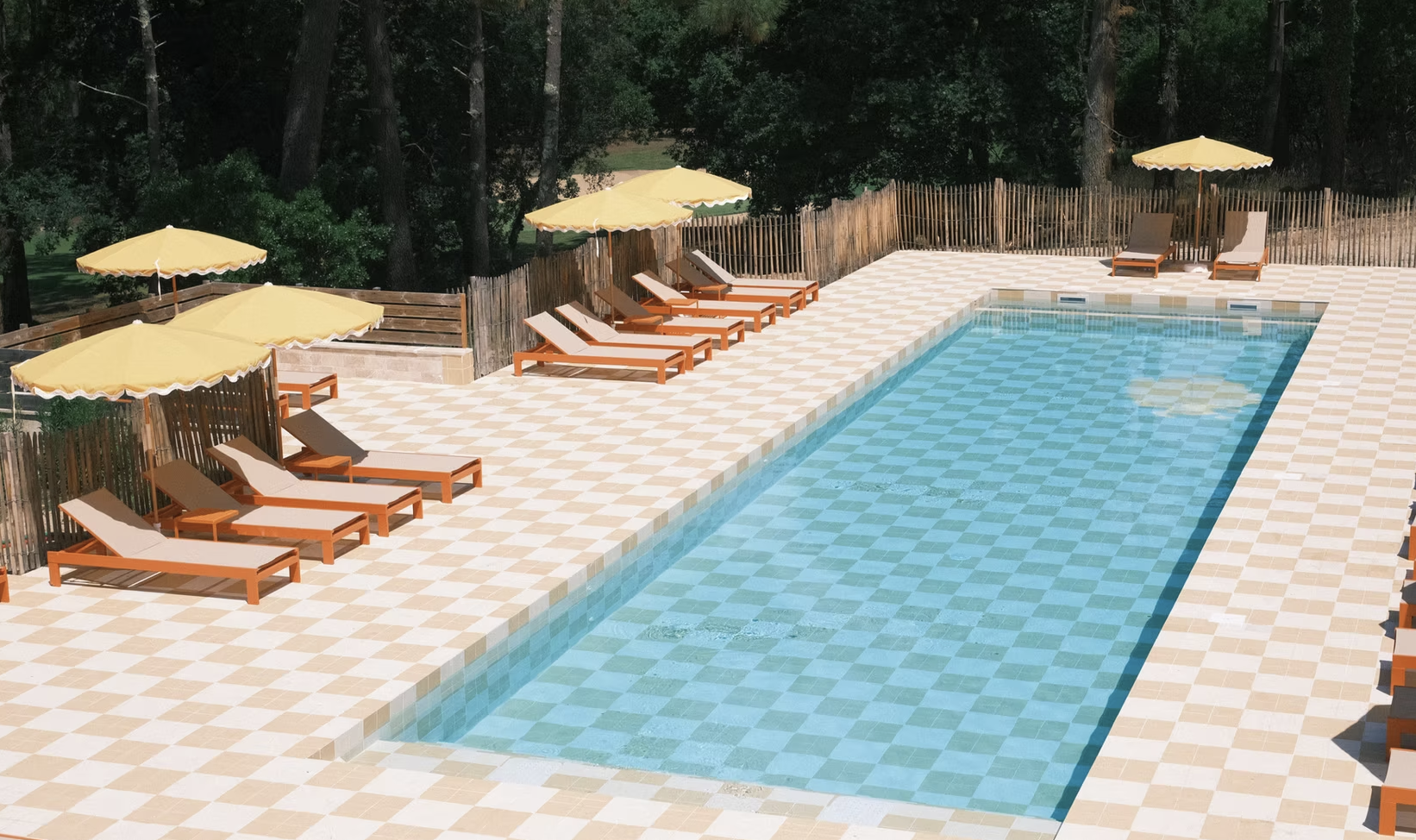 Piscine extérieure au carrelage damier entourée de pins landais, retraite bien-être yoga doux Lacanau