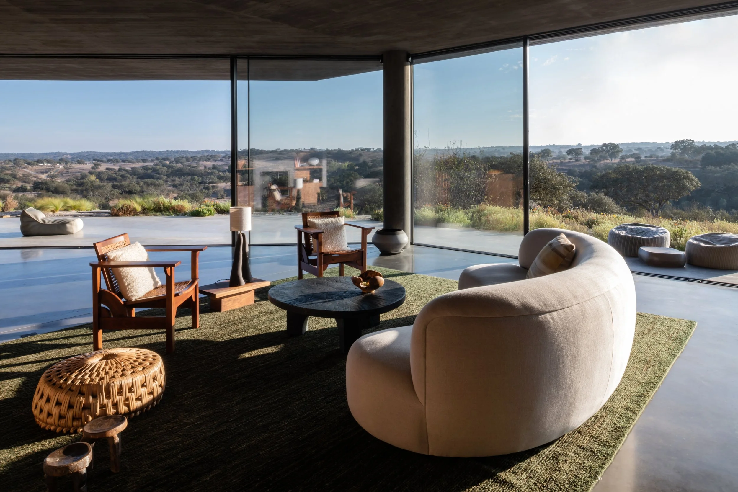Salon aux baies vitrées ouvert sur la plaine, lumière du coucher de soleil — villa retraite yoga Portugal