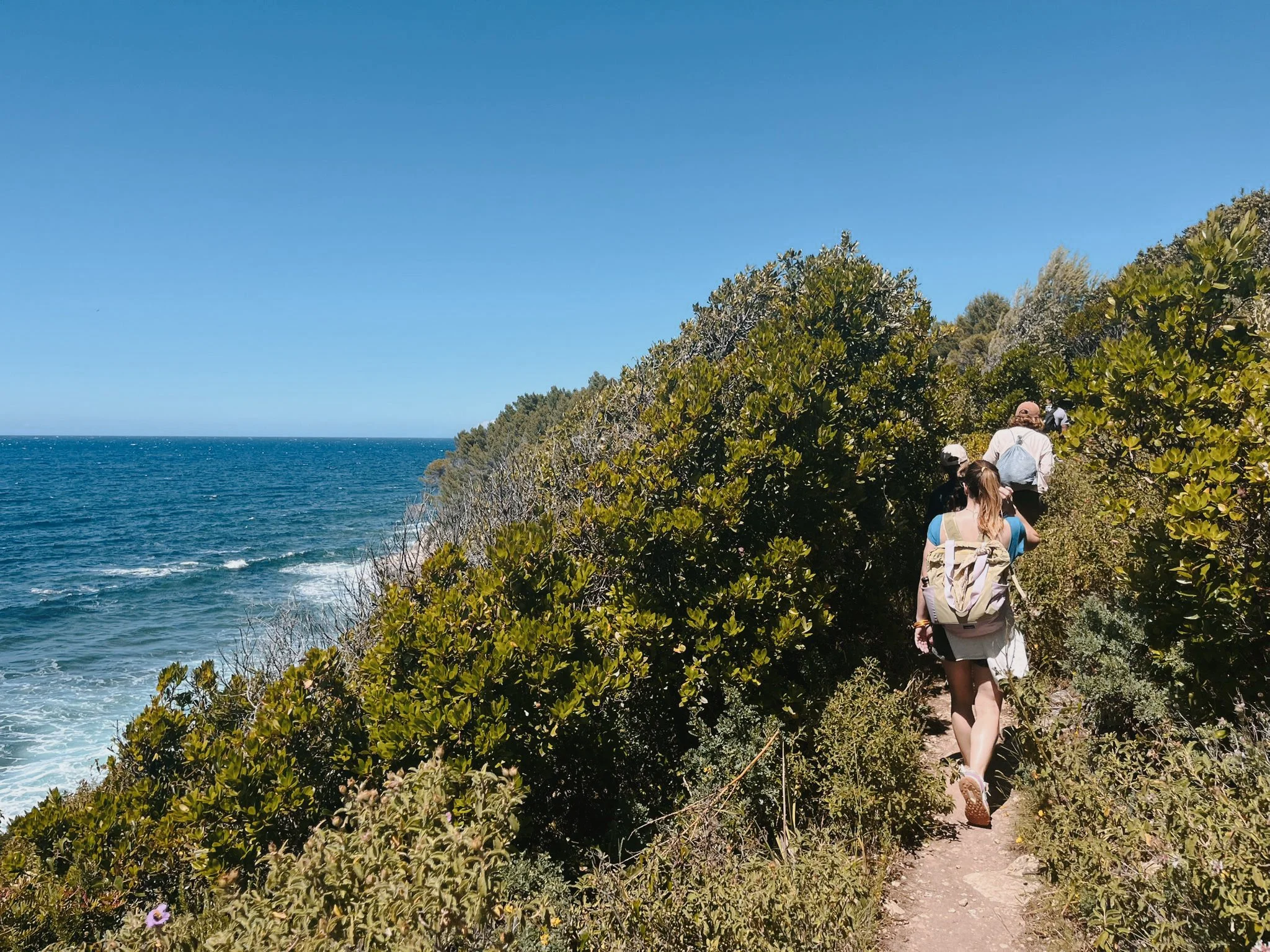 Femme sur un sentier côtier avec vue mer — marche méditative retraite yoga sororité Haute-Corse 2026