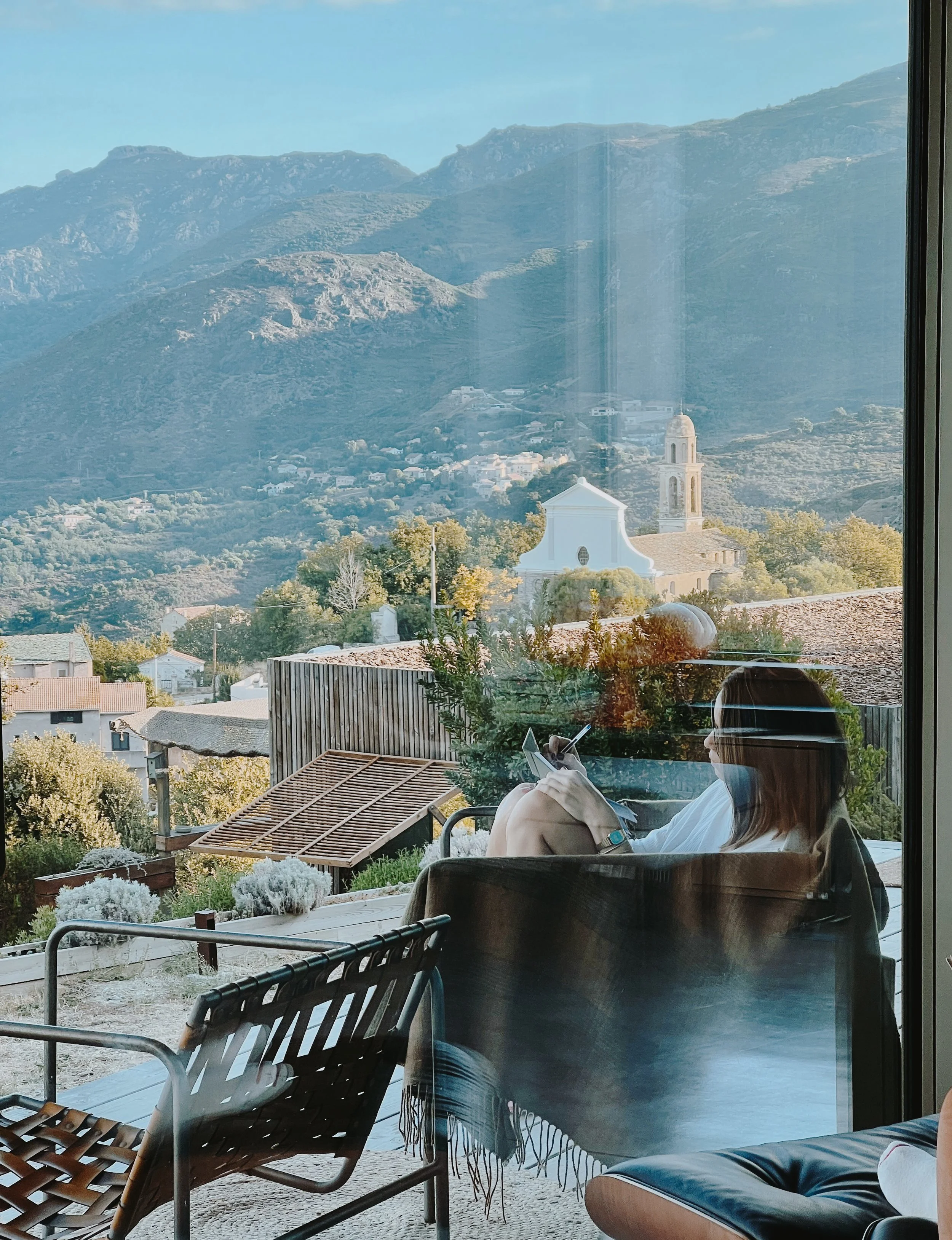 participante en train d’écrire face à la mer et aux montagnes corses, moment de réflexion et d’ancrage pendant la retraite yoga & randonnée du Yogascope