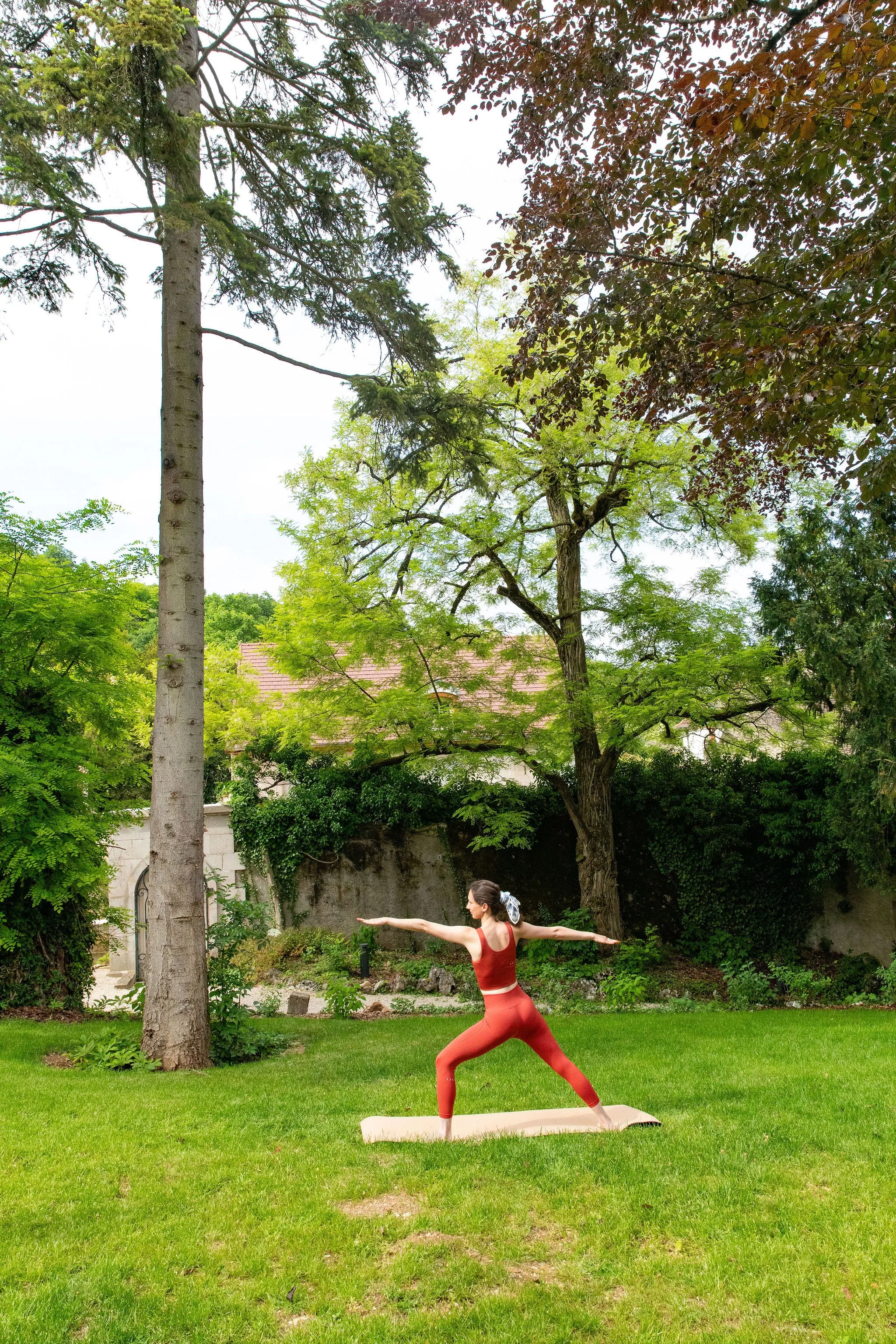 Pratique de yoga en extérieur dans un jardin arboré pendant la retraite bien-être en Bourgogne. Reconnexion à la nature, ancrage et sérénité.