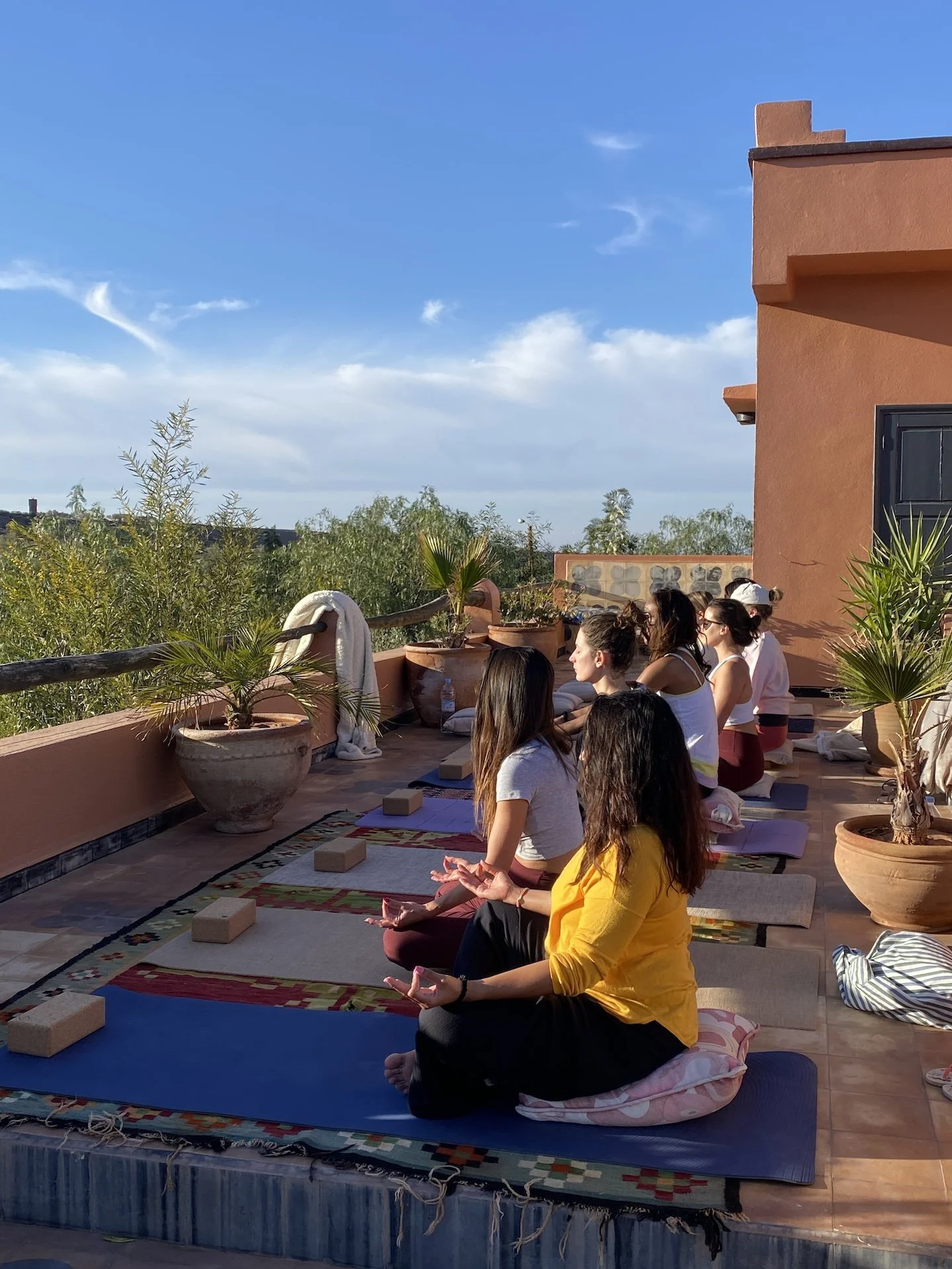 Groupe de femmes en séance de méditation sur la terrasse du riad — cours yoga Hatha Flow retraite bien-être Marrakech novembre 2026