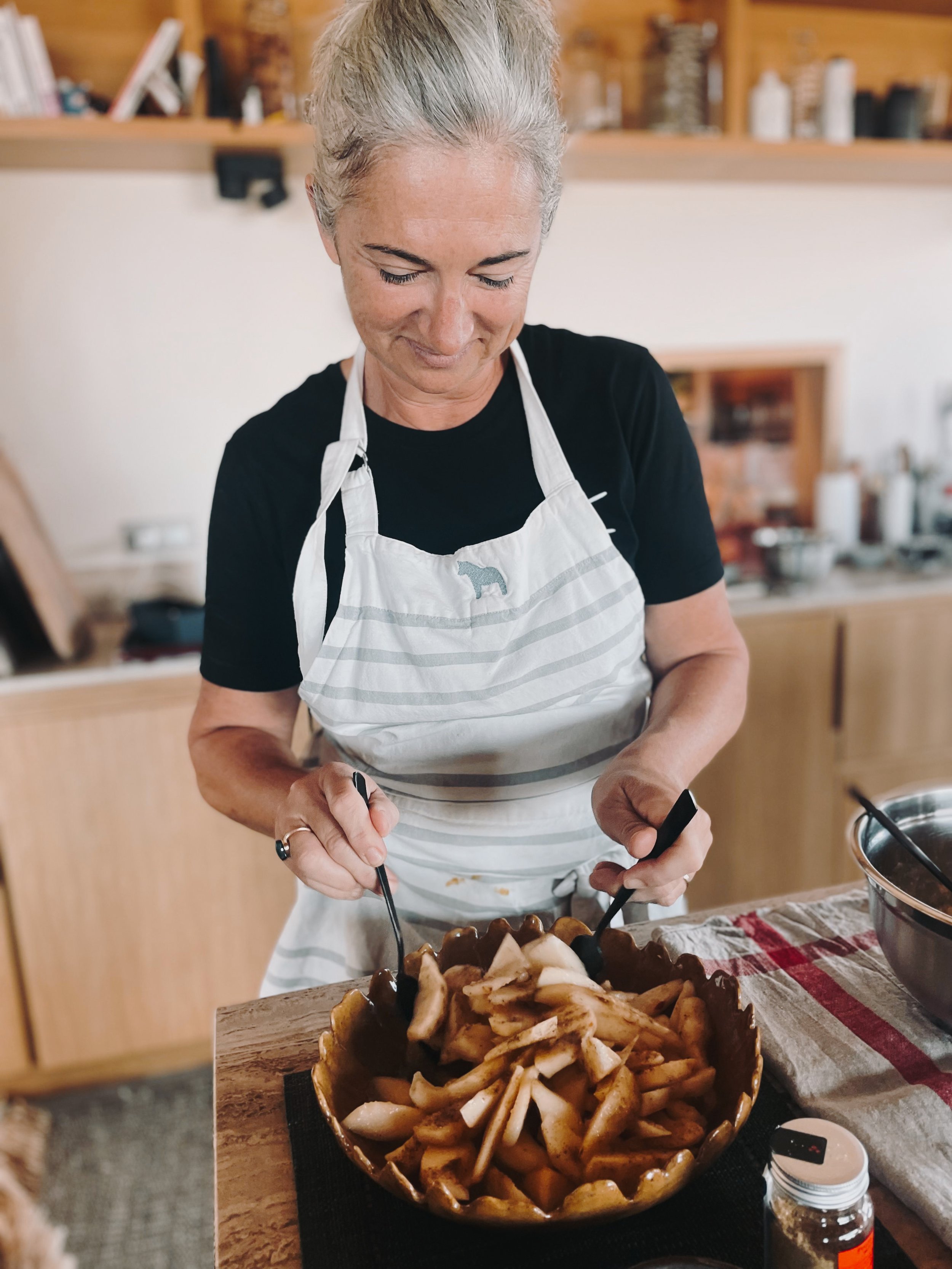 Élodie, l’hôte du lieu, prépare un repas maison dans la cuisine de la villa, incarnant l’art de recevoir et la générosité corse pendant la retraite yoga & bien-être
